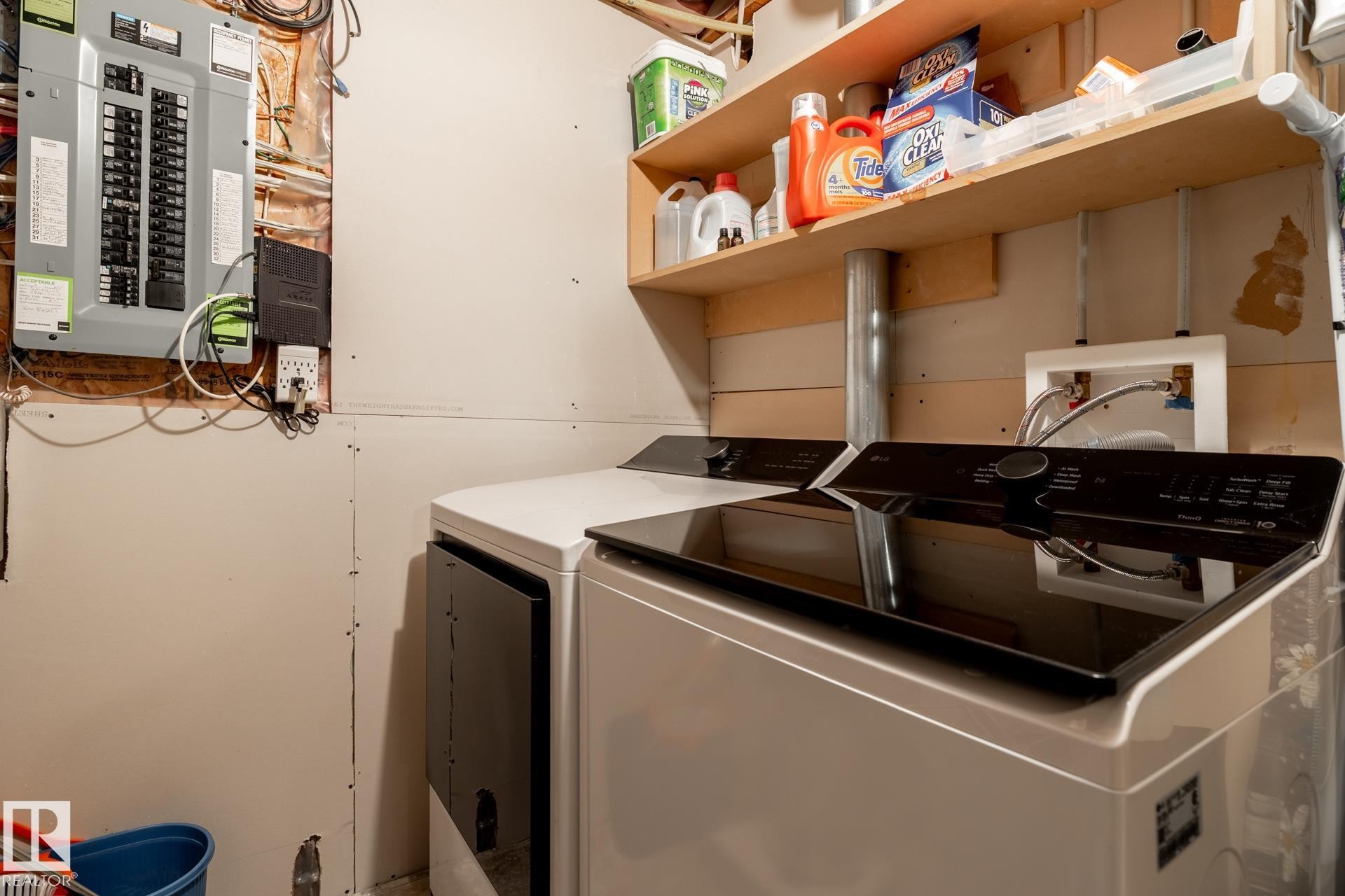Dedicated laundry area featuring a washer and dryer, wood shelving, and exposed electrical panel - 5820 7 Avenue Sw, Edmonton, AB - Indoor Photo Showing Laundry Room