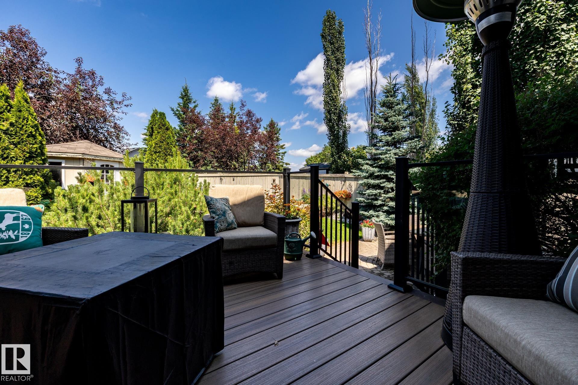 Expansive outdoor deck featuring wood-finish decking, dark railing, and mature landscaping - 5820 7 Avenue Sw, Edmonton, AB - Outdoor With Deck Patio Veranda