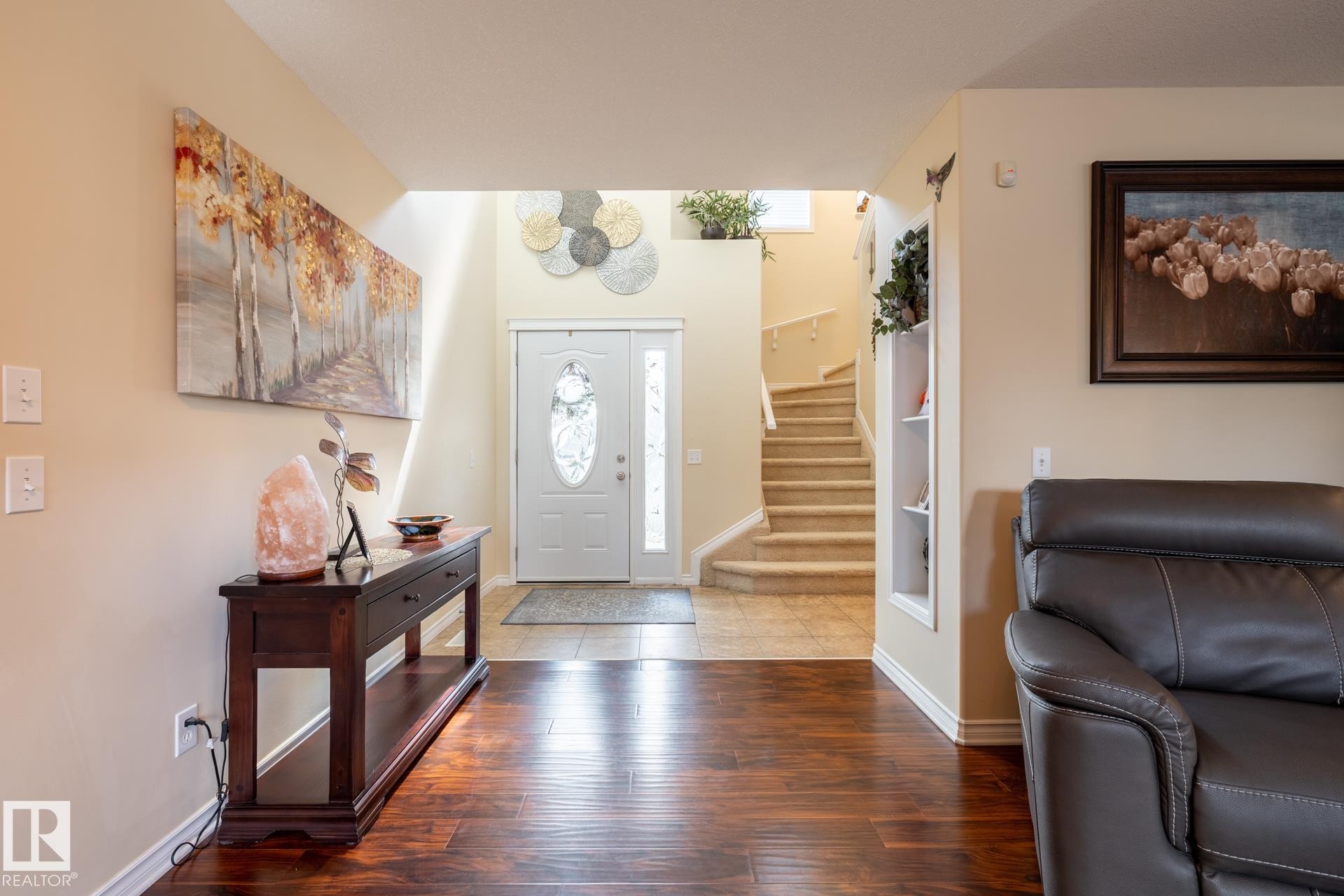 Bright entry foyer featuring wood-finish flooring, a white paneled door with decorative glass inserts, and a tiled entryway - 5820 7 Avenue Sw, Edmonton, AB - Indoor Photo Showing Living Room