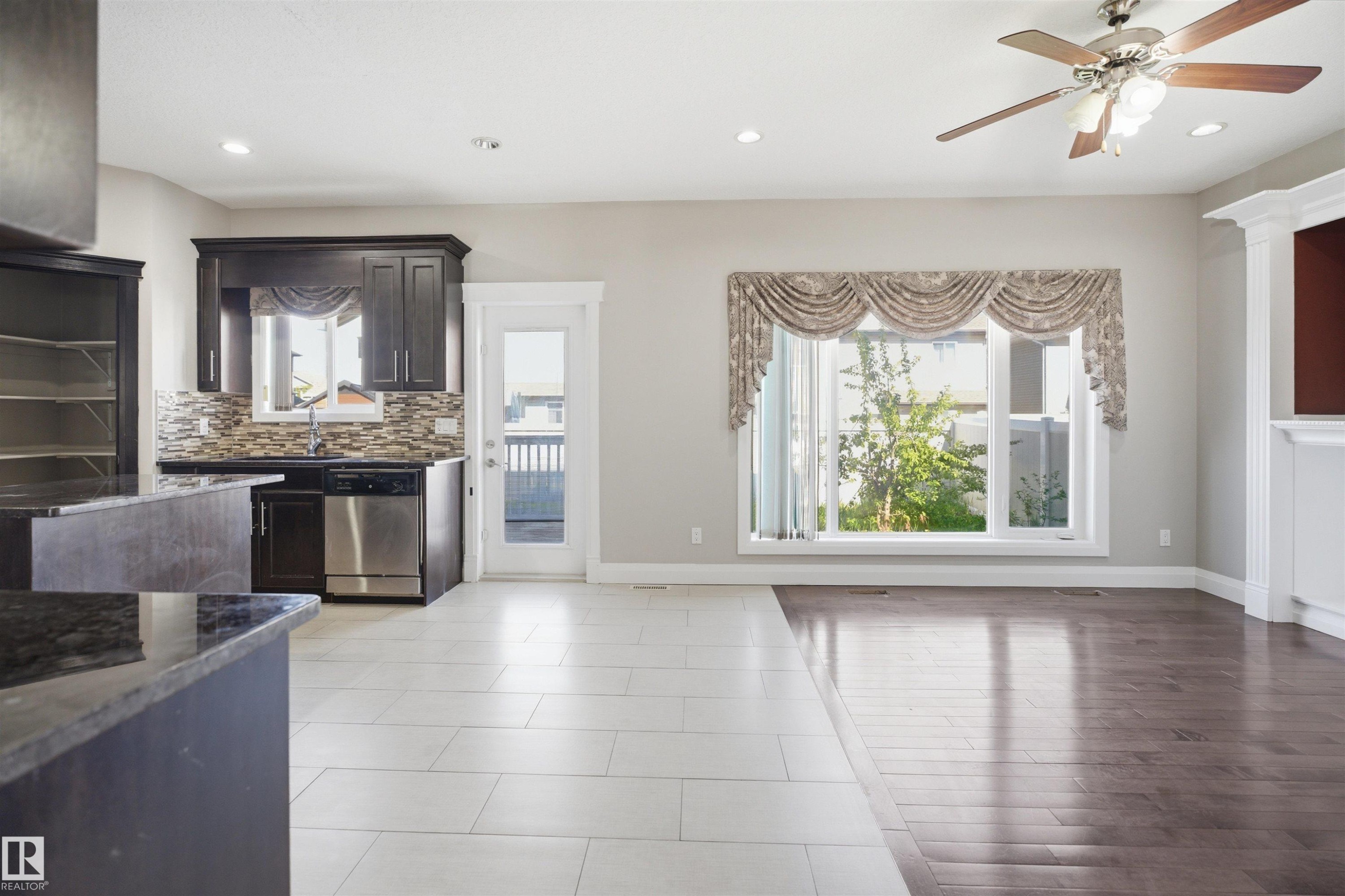Spacious open-concept living area featuring a large window with decorative valance, recessed lighting, and a ceiling fan - 16807 54 Street, Edmonton, AB - Indoor Photo Showing Other Room With Fireplace