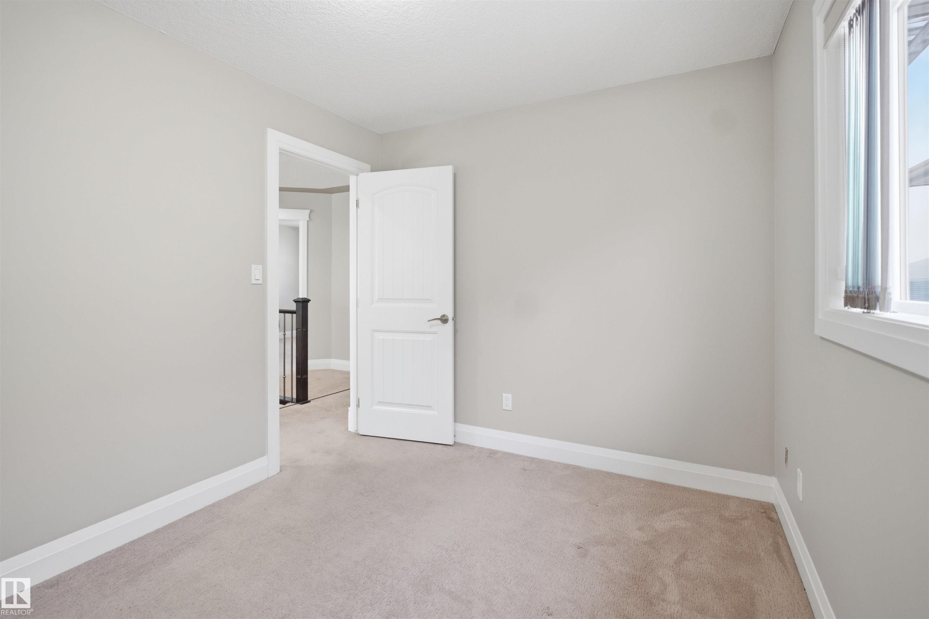 Interior room featuring light gray walls, white trim, and neutral carpeting - 16807 54 Street, Edmonton, AB - Indoor Photo Showing Other Room