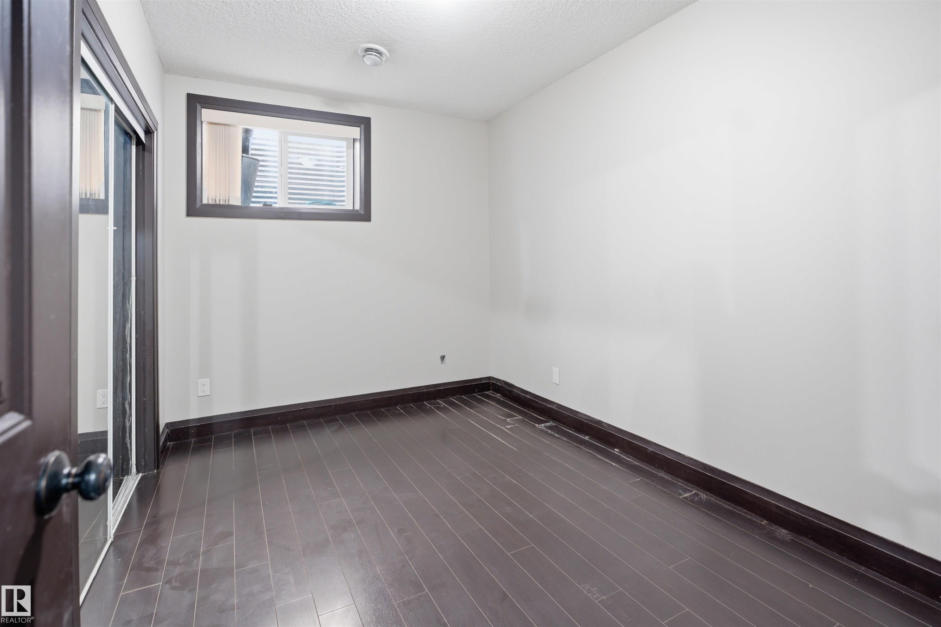 Room featuring dark wood-finish flooring, white walls, and dark trim - 16807 54 Street, Edmonton, AB - Indoor Photo Showing Other Room