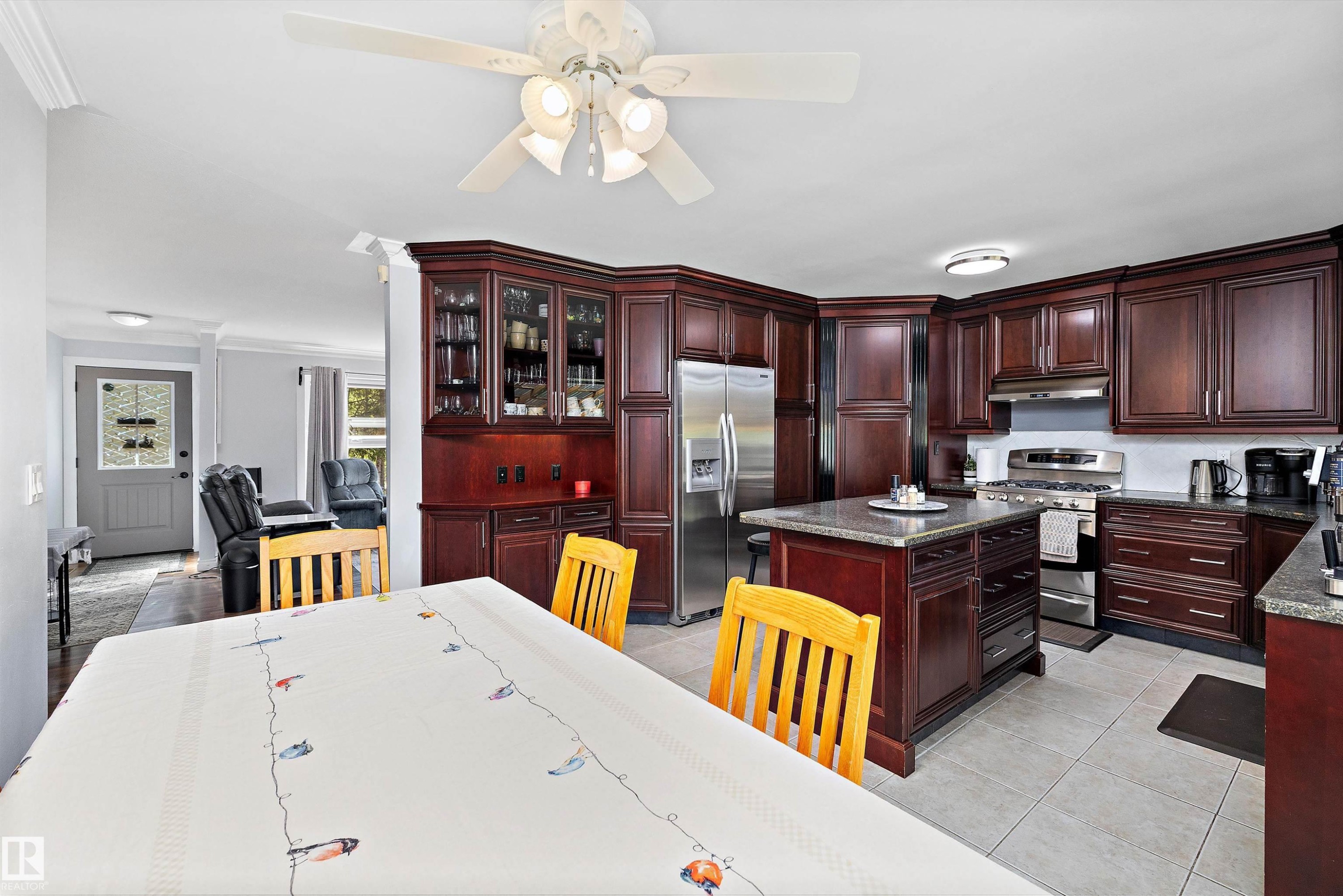 Kitchen featuring rich wood cabinetry, stainless steel appliances, a center island with a stone-finish countertop, tile flooring, and recessed lighting - 53257 Rge Road 211, Rural Strathcona County, AB - Indoor
