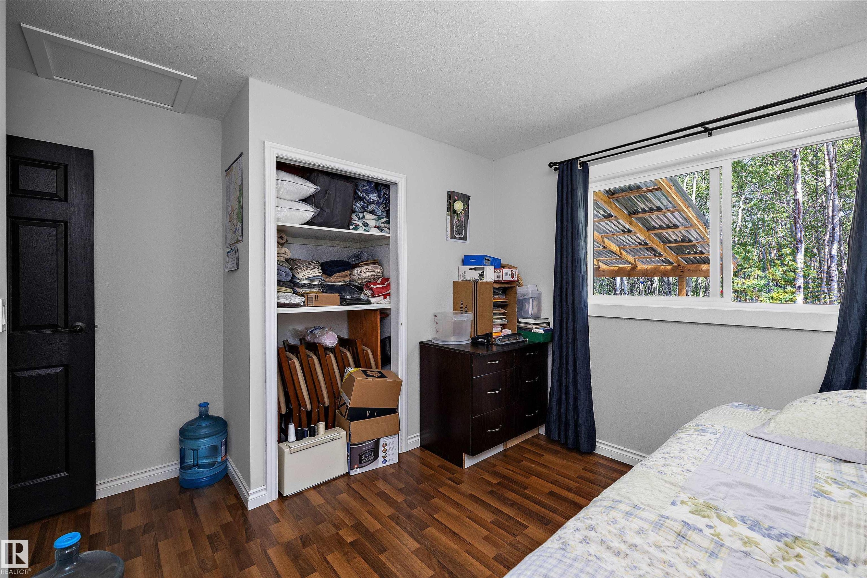 Room featuring wood-finish flooring, a white-framed window, and a built-in closet with shelving - 53257 Rge Road 211, Rural Strathcona County, AB - Indoor Photo Showing Bedroom