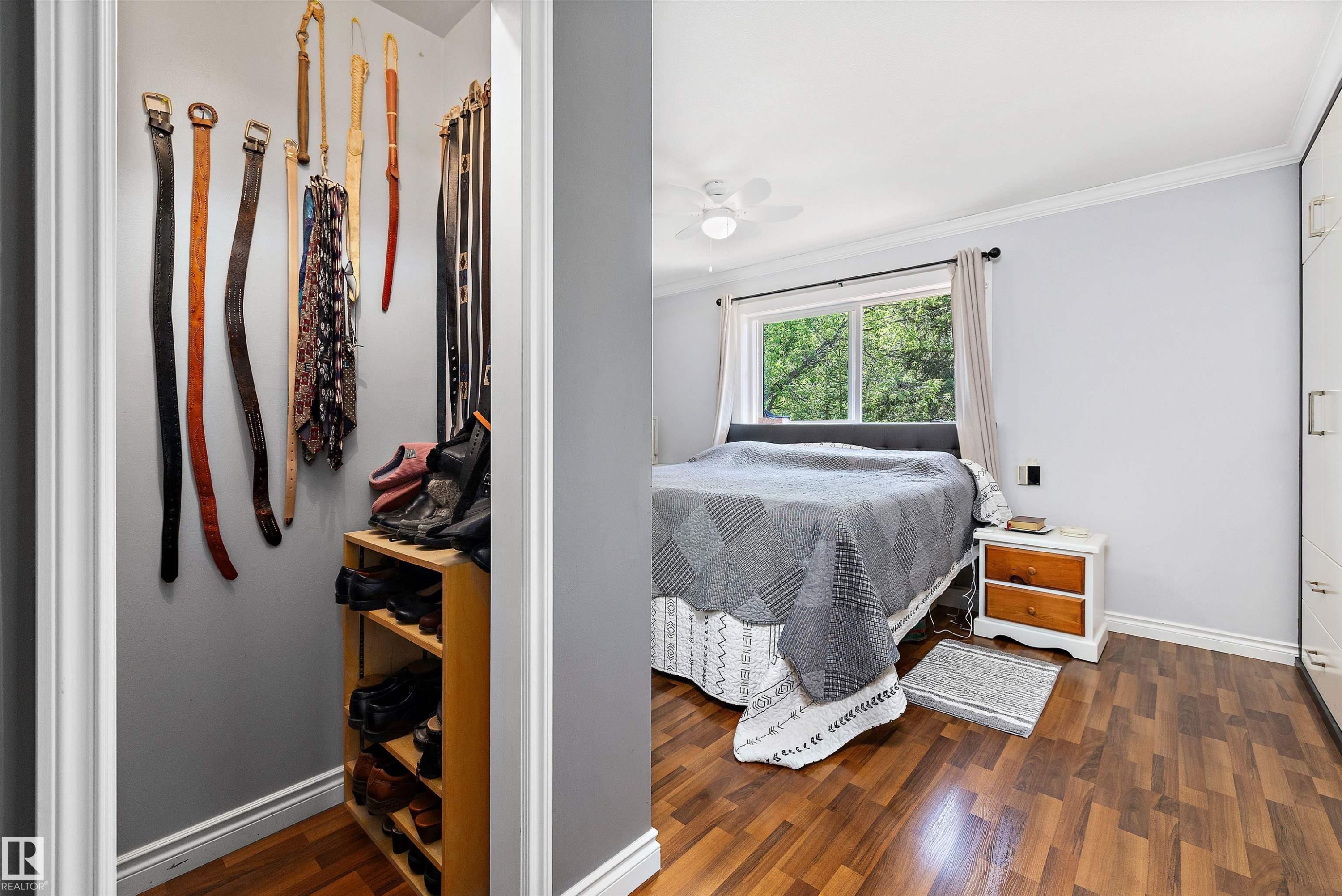 Bedroom featuring wood-finish flooring, a white ceiling fan, and a large window with white trim - 53257 Rge Road 211, Rural Strathcona County, AB - Indoor Photo Showing Other Room