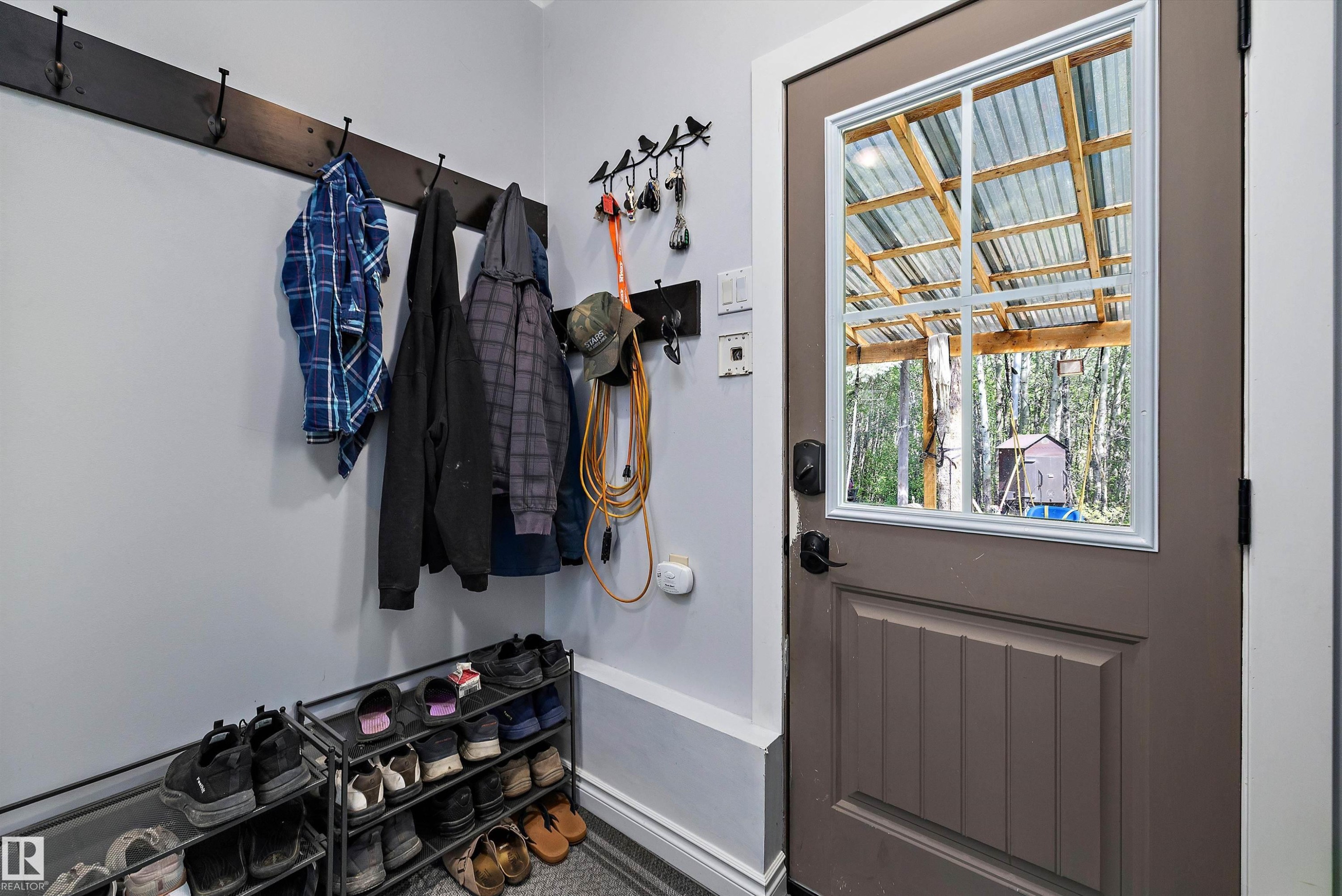 Entryway featuring a panel door with a window insert, wall-mounted coat hooks, and a neutral wall color - 53257 Rge Road 211, Rural Strathcona County, AB - Indoor