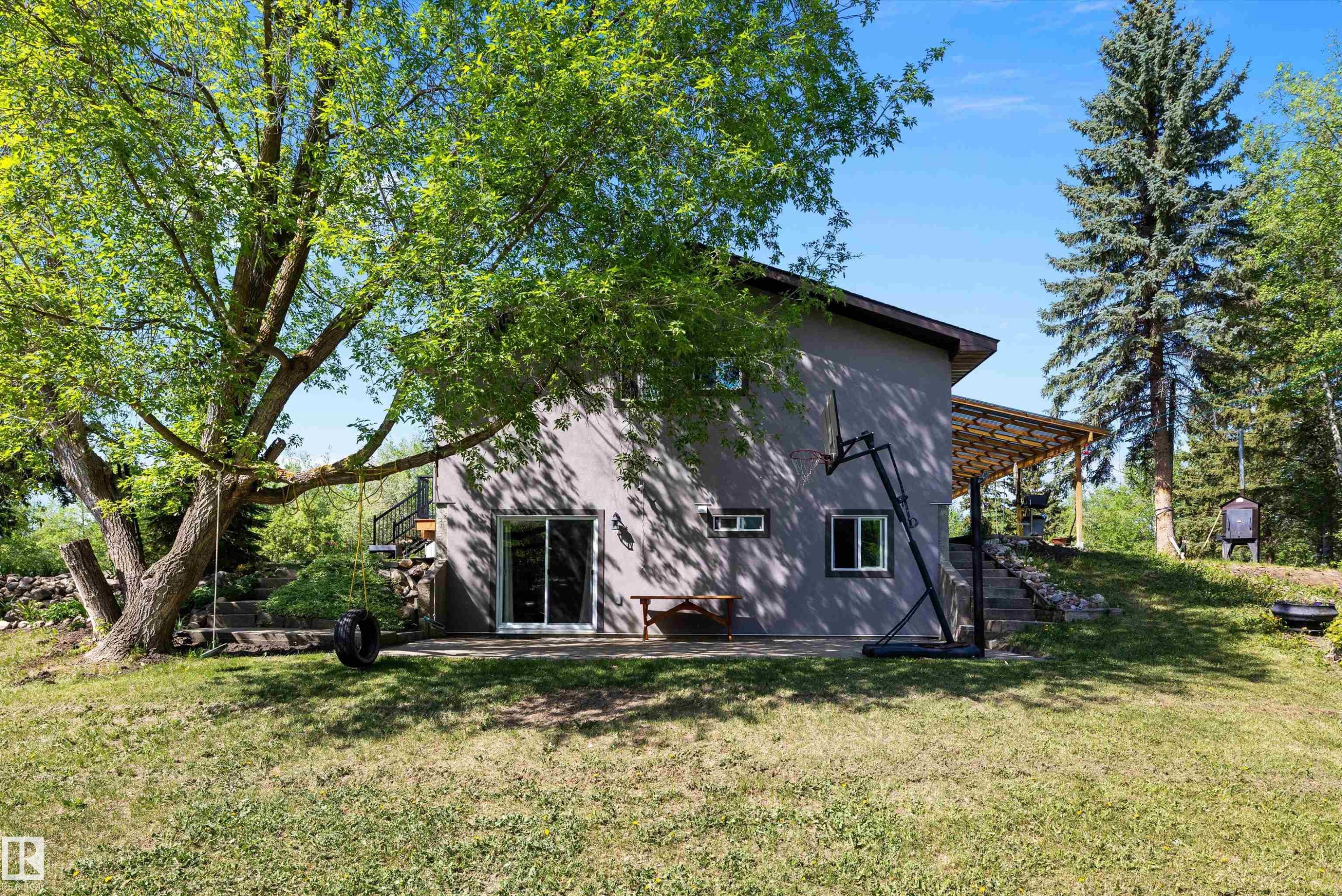 Rear exterior featuring a sliding glass patio door, stucco siding, and a covered porch - 53257 Rge Road 211, Rural Strathcona County, AB - Outdoor