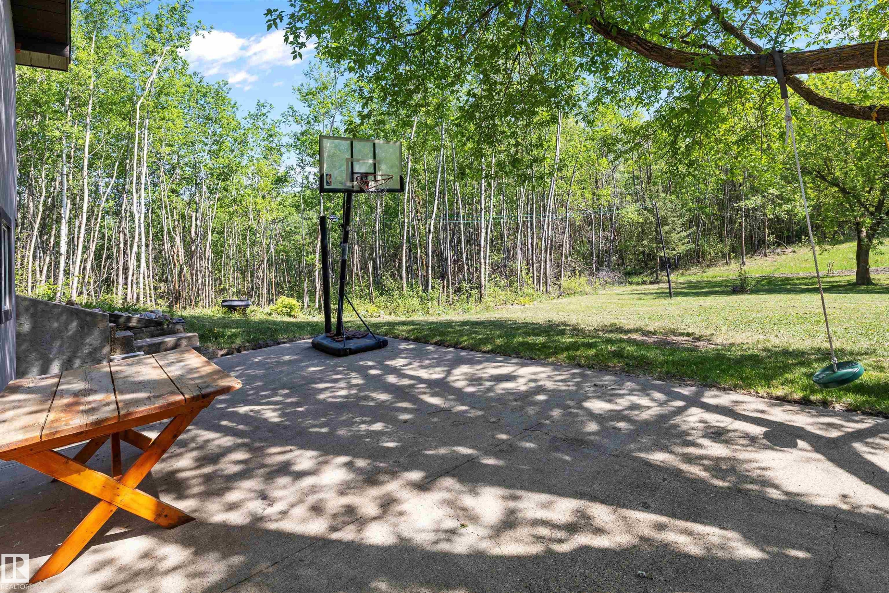 Expansive concrete patio with a lush green lawn and mature trees - 53257 Rge Road 211, Rural Strathcona County, AB - Outdoor