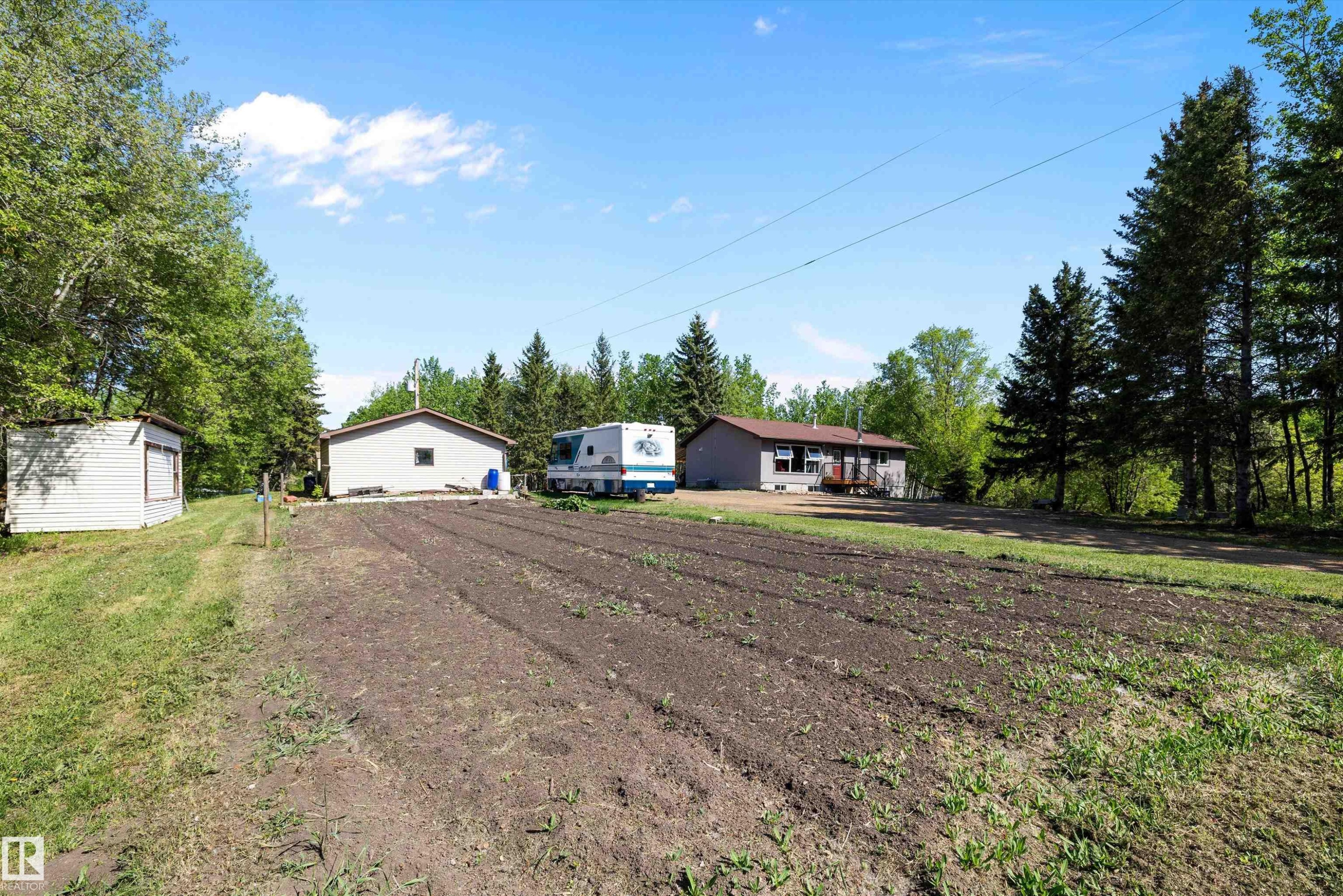 Expansive plot of cultivated land with a backdrop of mature evergreen and deciduous trees - 53257 Rge Road 211, Rural Strathcona County, AB - Outdoor