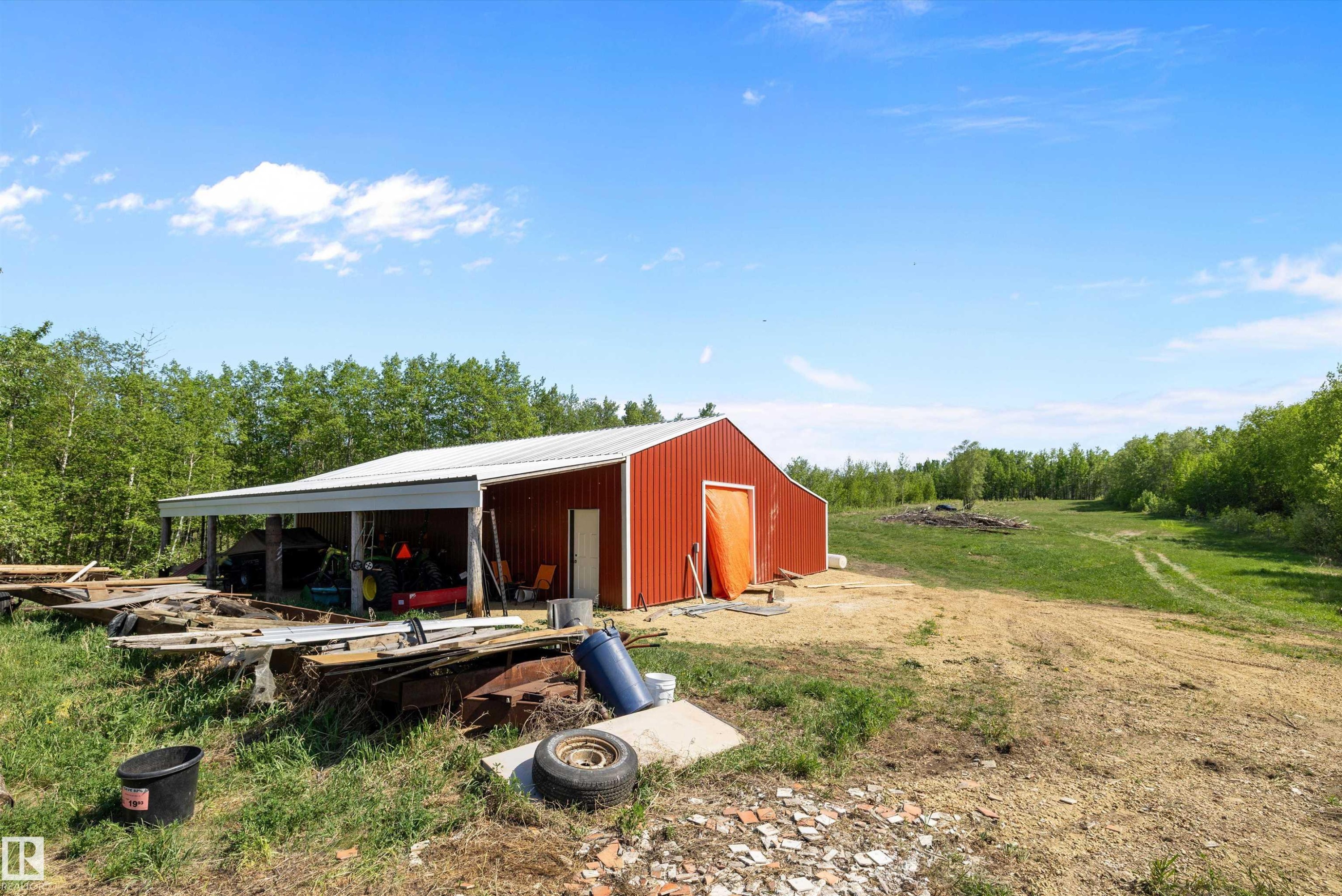 Red metal barn with a white corrugated metal roof and an integrated overhang providing covered storage - 53257 Rge Road 211, Rural Strathcona County, AB - Outdoor