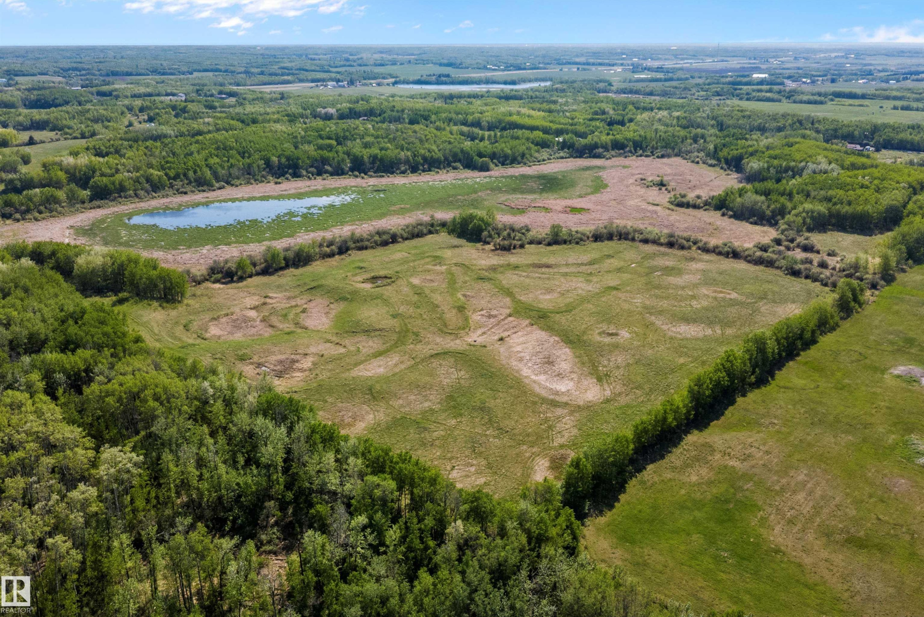 Expansive land parcel featuring open fields, a natural pond, and mature tree lines - 53257 Rge Road 211, Rural Strathcona County, AB - Outdoor With View
