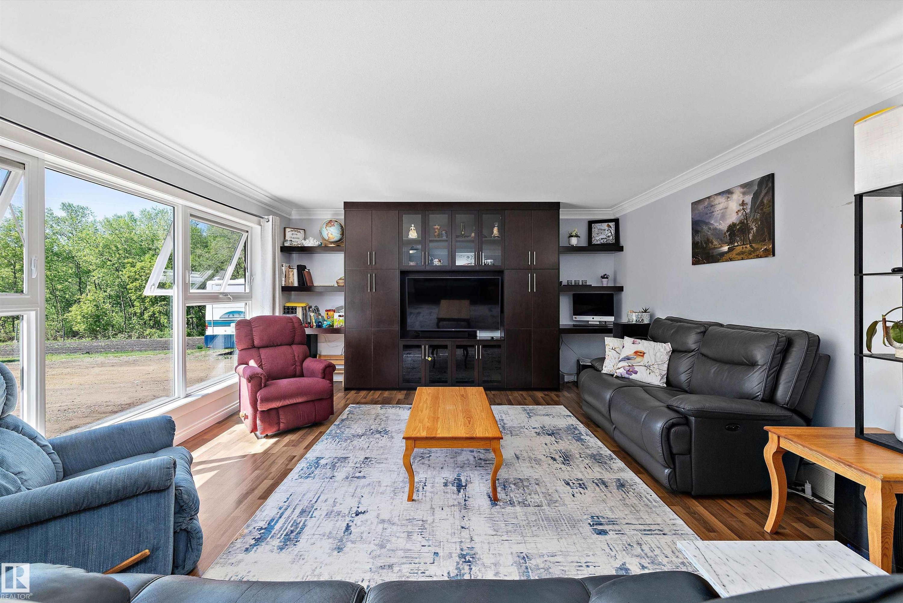 Spacious living area featuring large picture windows, wood-finish flooring, and a built-in media center with shelving - 53257 Rge Road 211, Rural Strathcona County, AB - Indoor Photo Showing Living Room