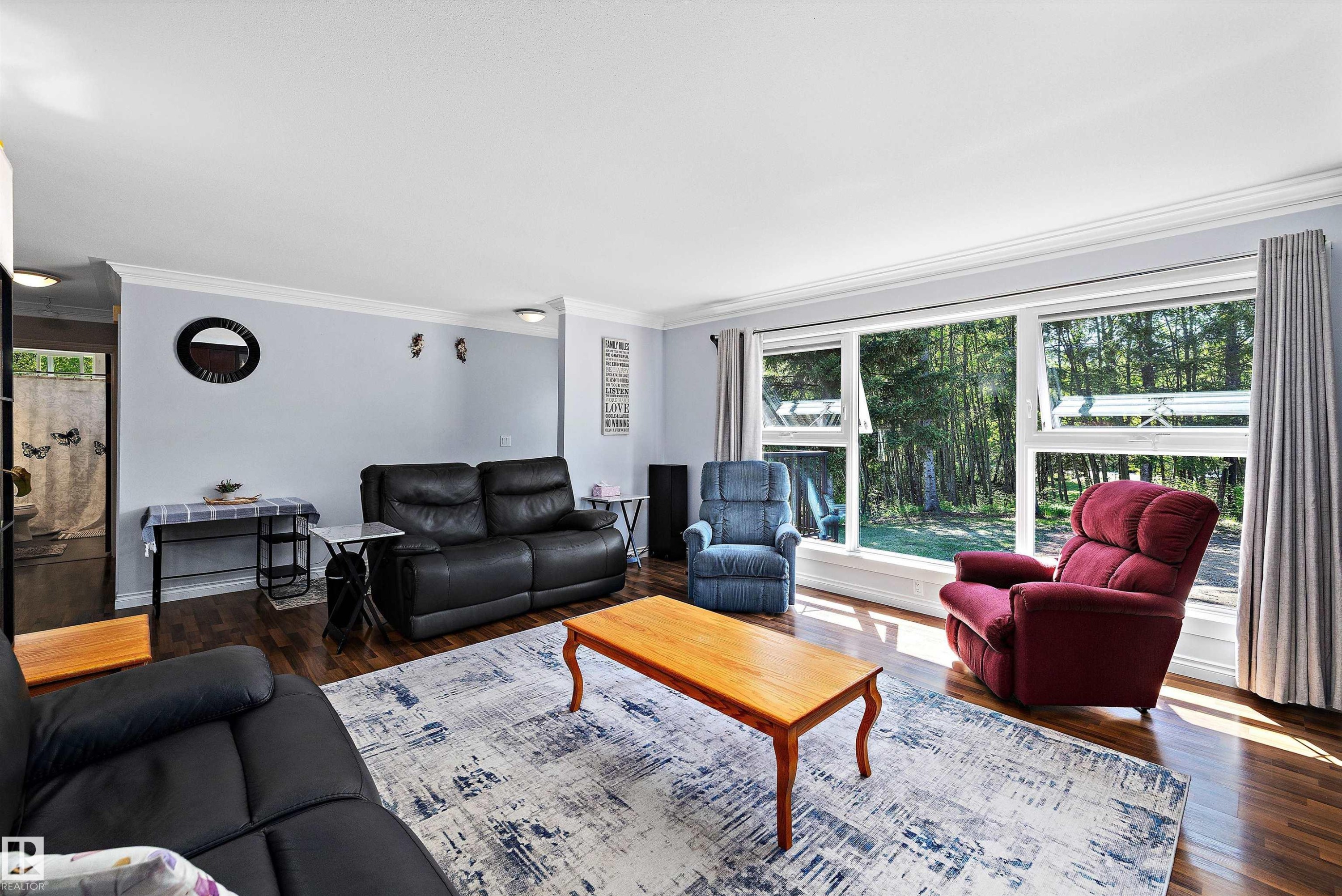 Spacious living area featuring large picture windows, wood-finish flooring, light blue walls, and white crown molding - 53257 Rge Road 211, Rural Strathcona County, AB - Indoor Photo Showing Living Room