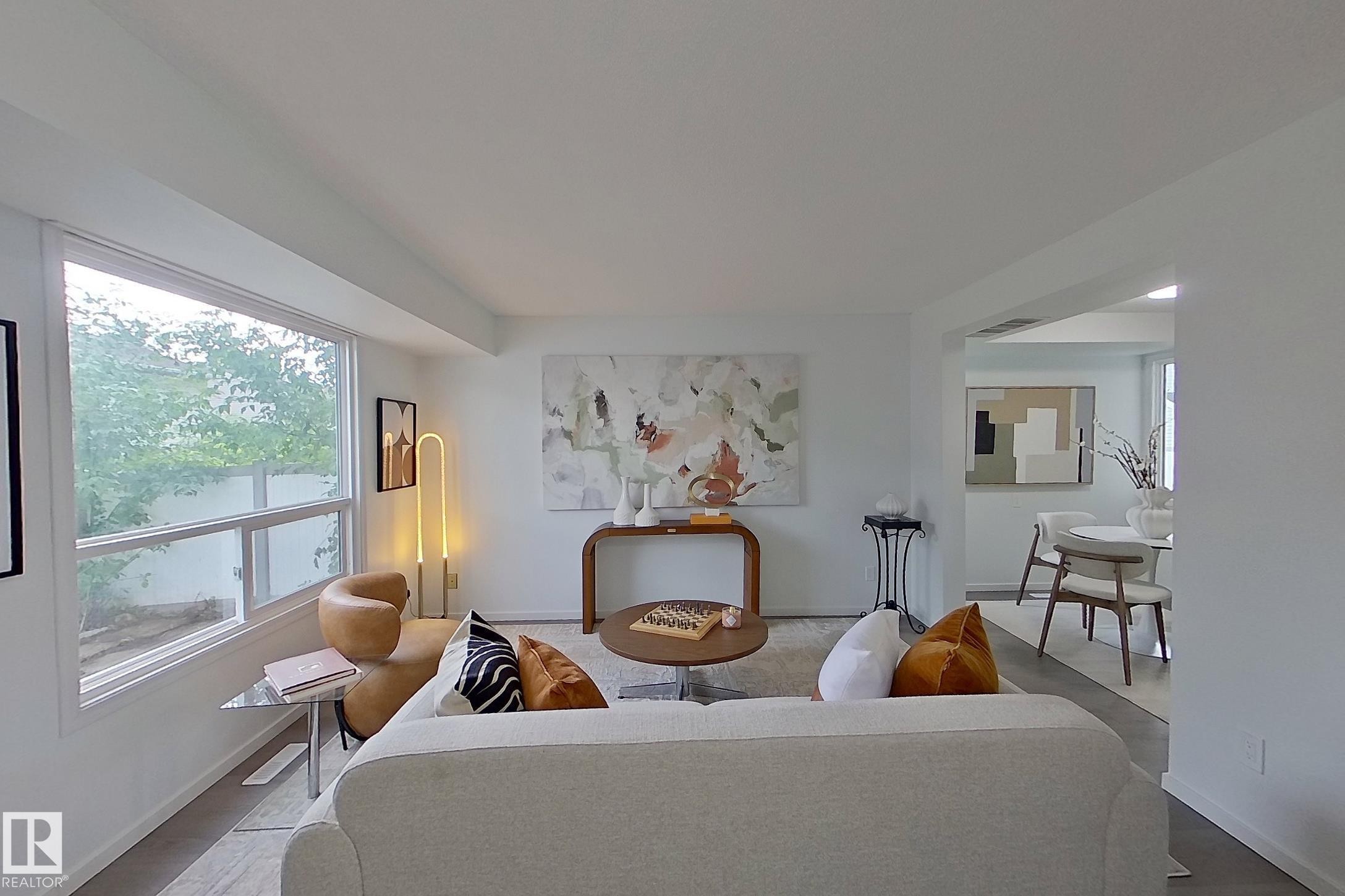 Light-filled living area featuring white walls and wood-finish flooring - 209 Dickinsfield Court Nw, Edmonton, AB