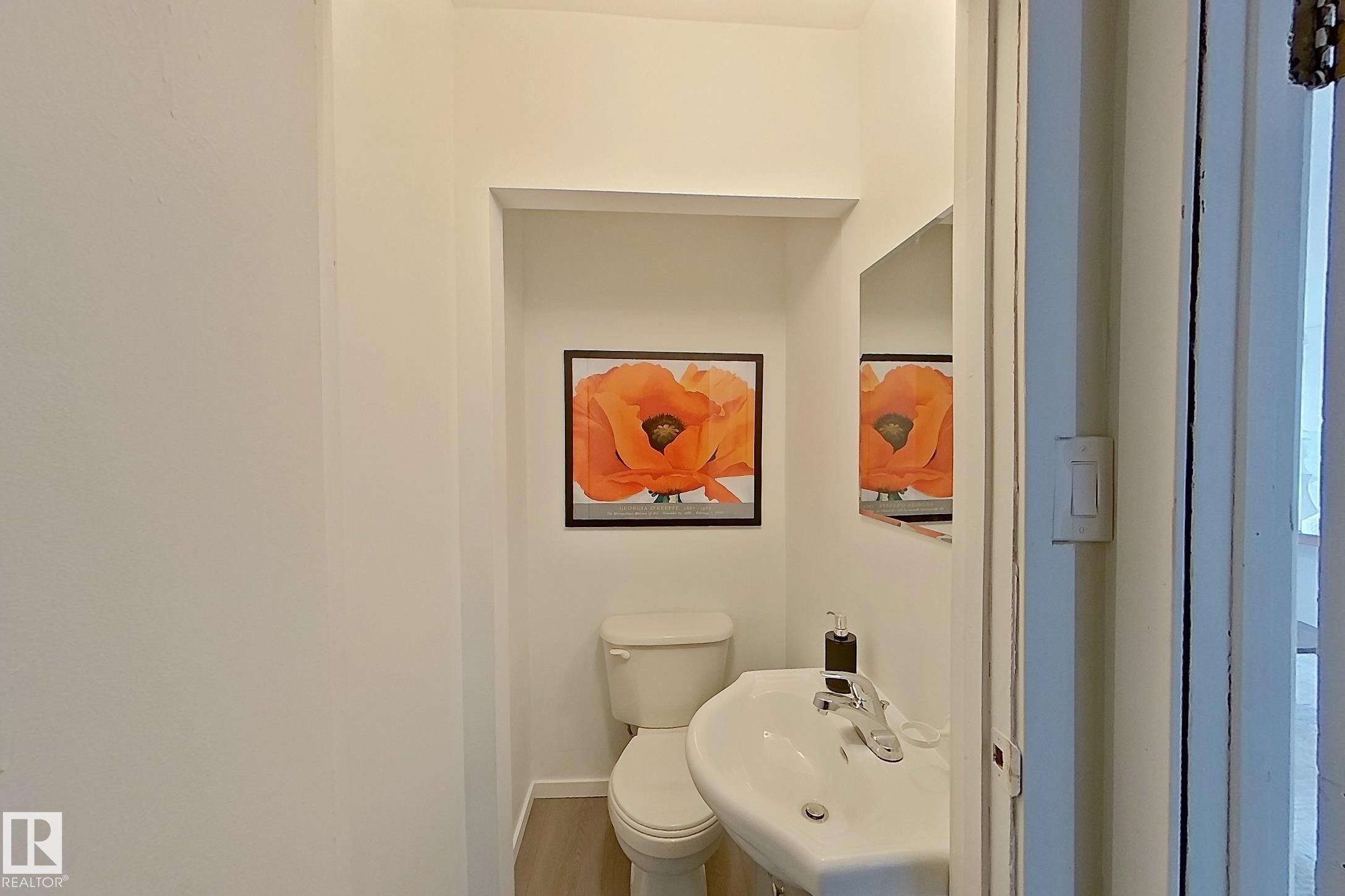 White pedestal sink with chrome faucet, white toilet, and recessed wall shelving - 209 Dickinsfield Court Nw, Edmonton, AB