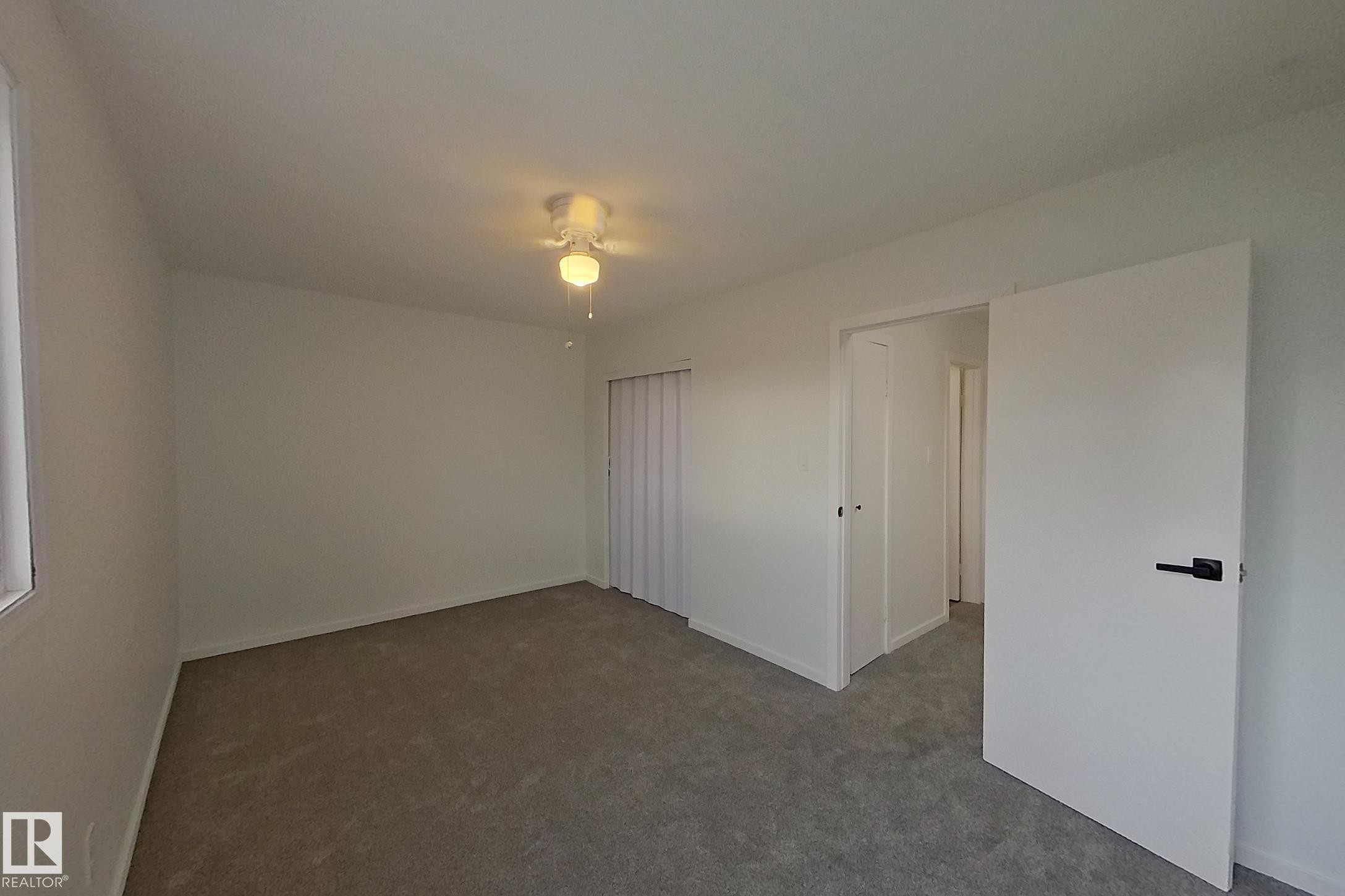 Interior room featuring light gray carpet flooring, white walls, and a ceiling fan with light fixture - 209 Dickinsfield Court Nw, Edmonton, AB