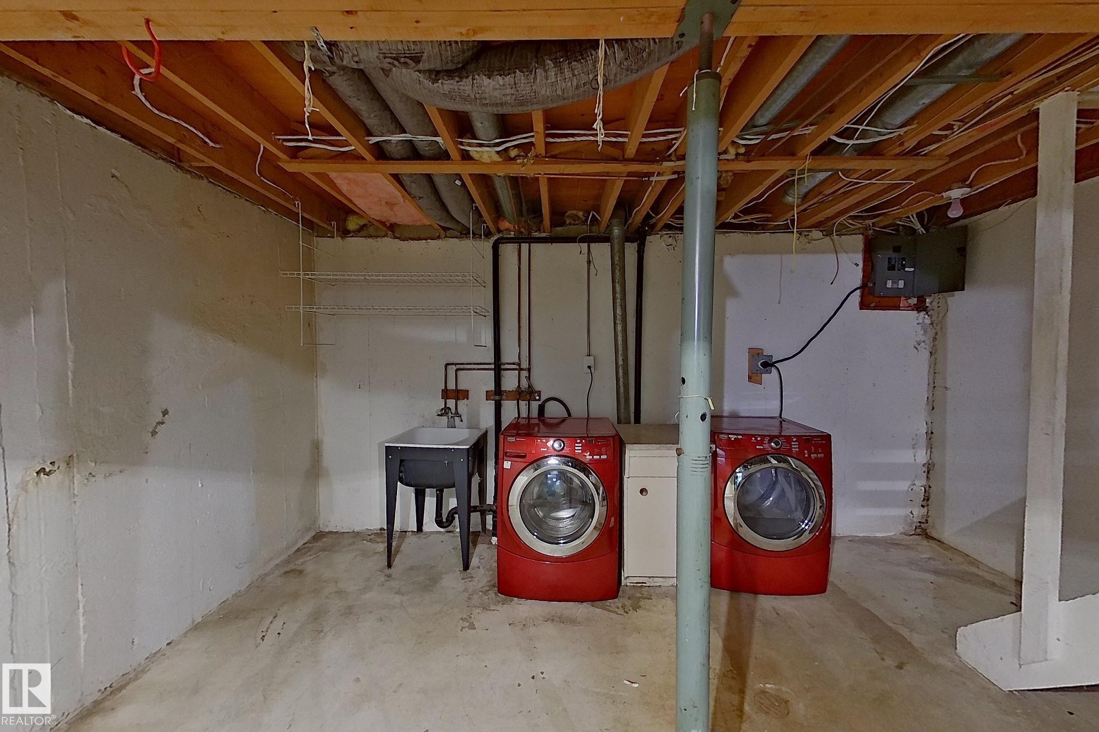 Unfinished basement space featuring exposed wood joists and concrete flooring - 209 Dickinsfield Court Nw, Edmonton, AB