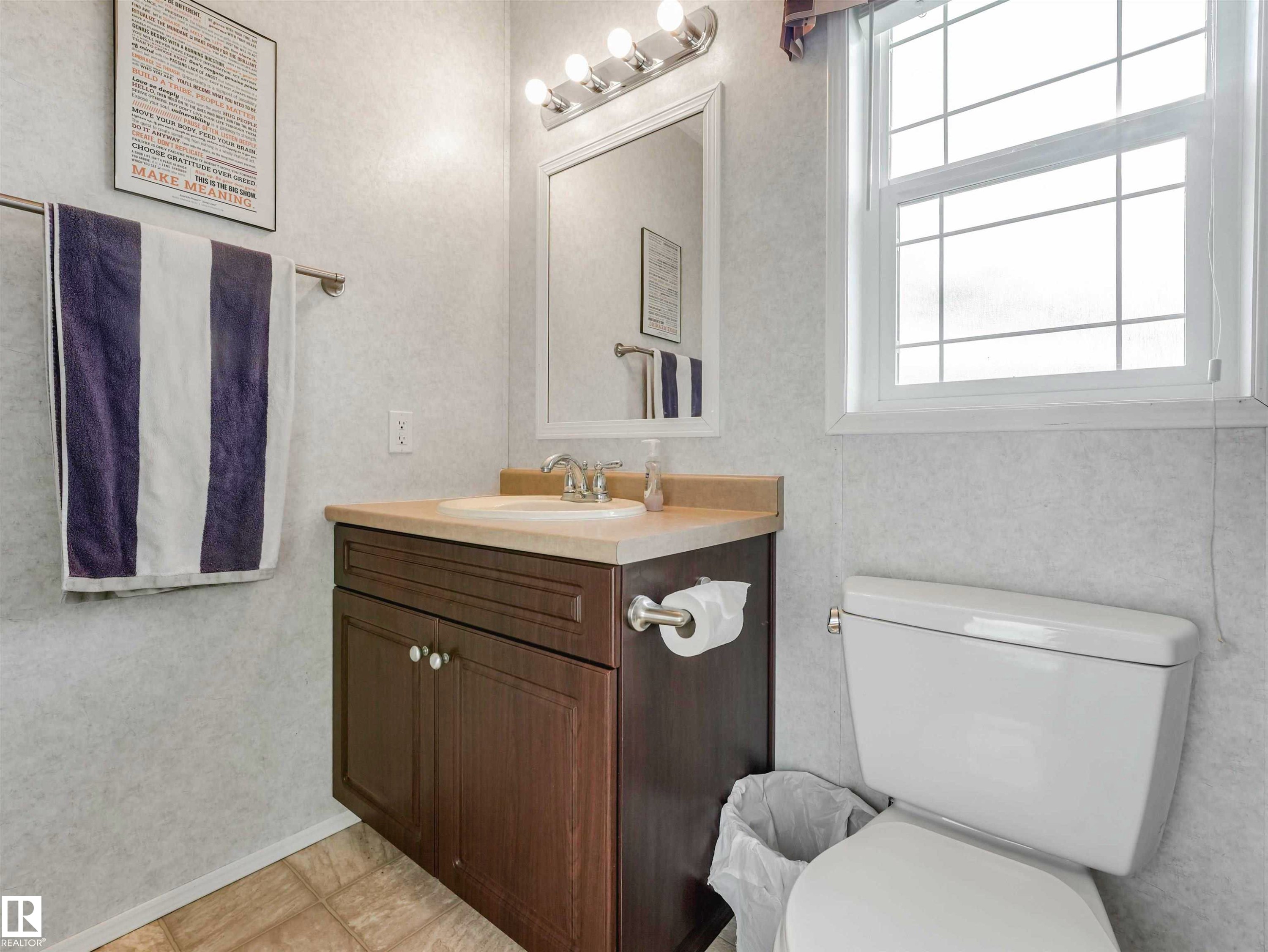 Bathroom vanity with a light-toned countertop, undermount sink, and two-door cabinet storage - 57016 Range Road 13, Rural Barrhead County, AB - Indoor Photo Showing Bathroom