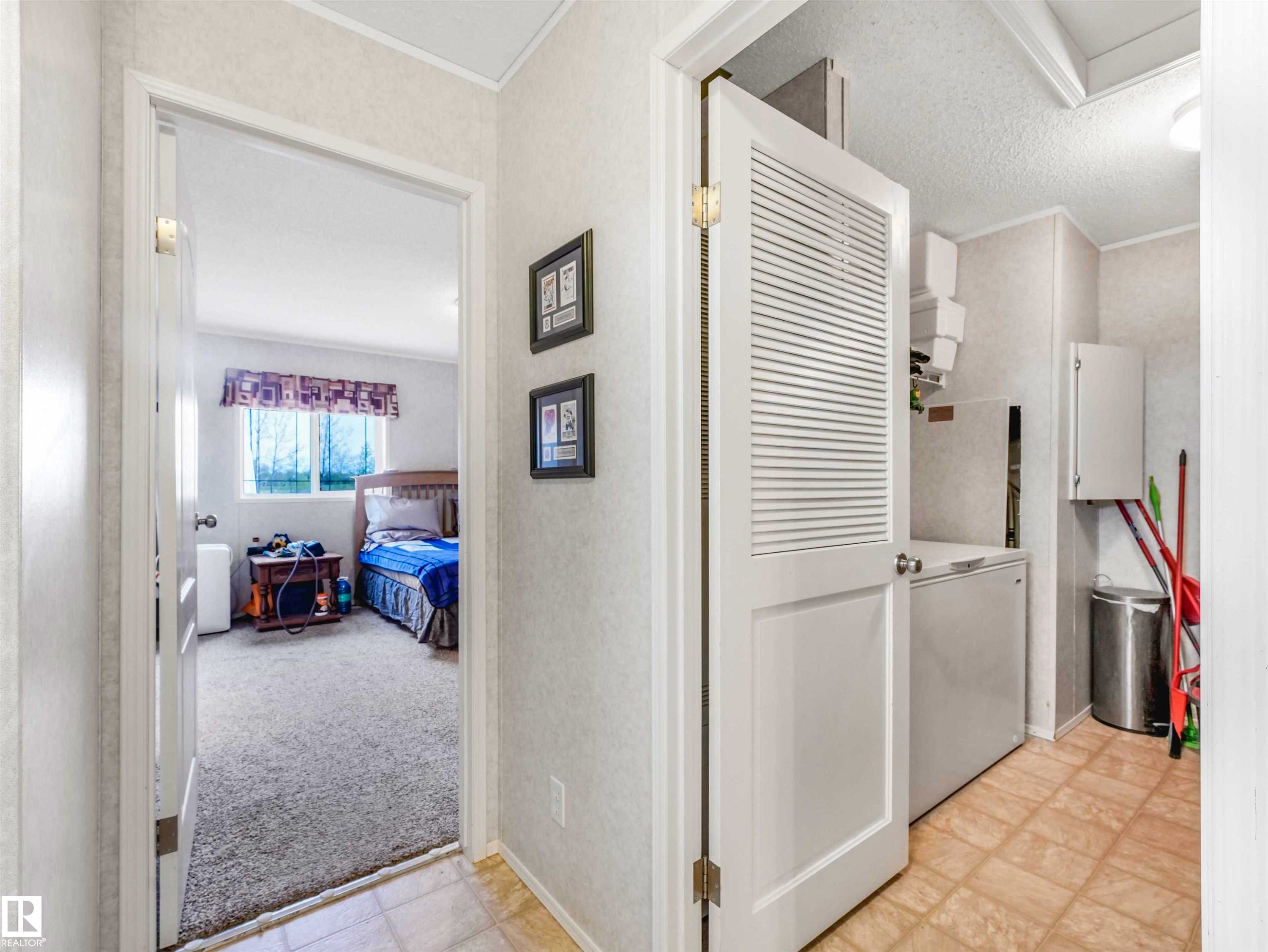 Louvered bi-fold door revealing a dedicated laundry area with tiled flooring and wall-mounted cabinetry - 57016 Range Road 13, Rural Barrhead County, AB - Indoor
