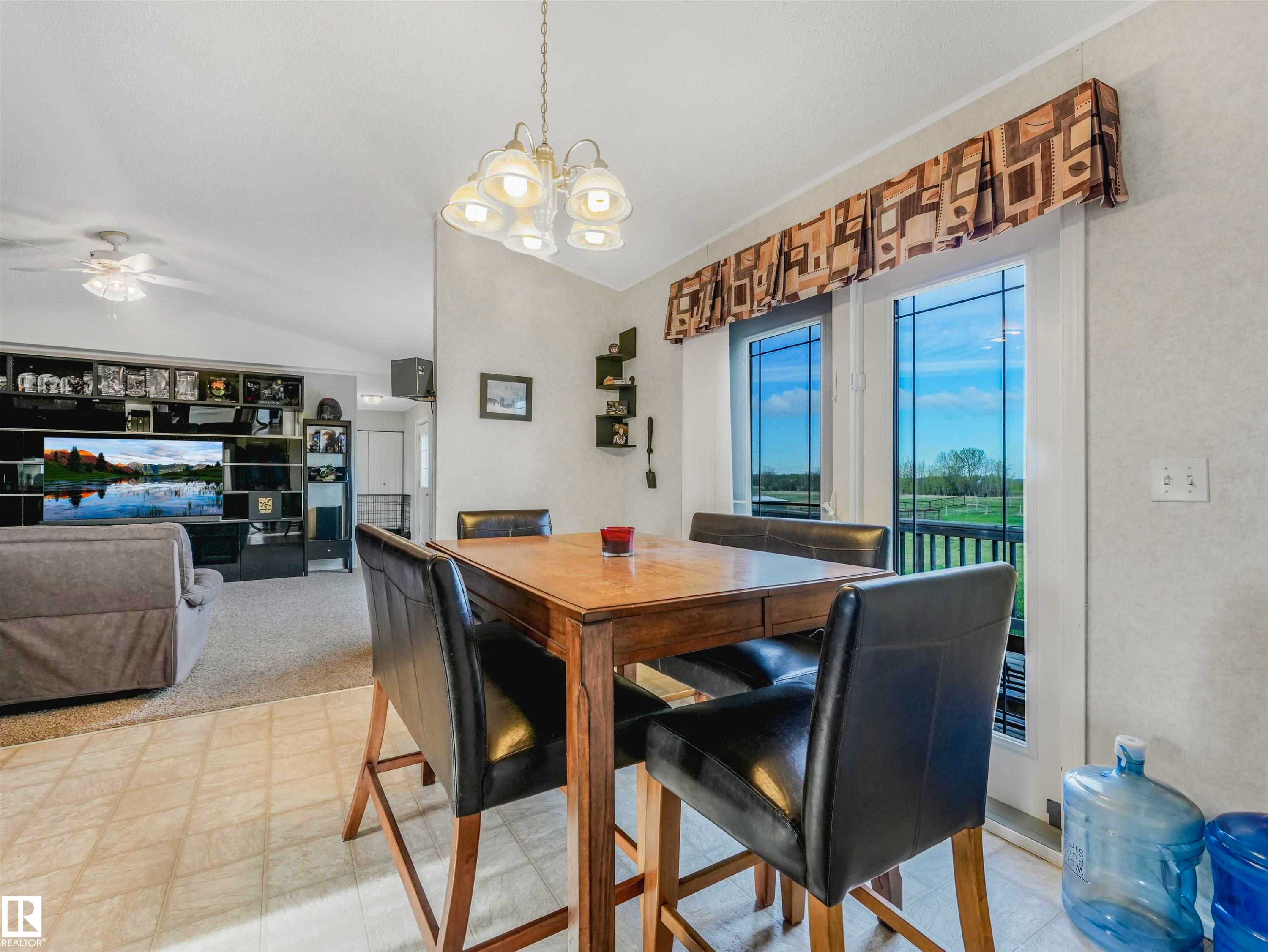 Dining area featuring a contemporary chandelier, a light-toned wood-finish table, and tile flooring - 57016 Range Road 13, Rural Barrhead County, AB - Indoor Photo Showing Dining Room