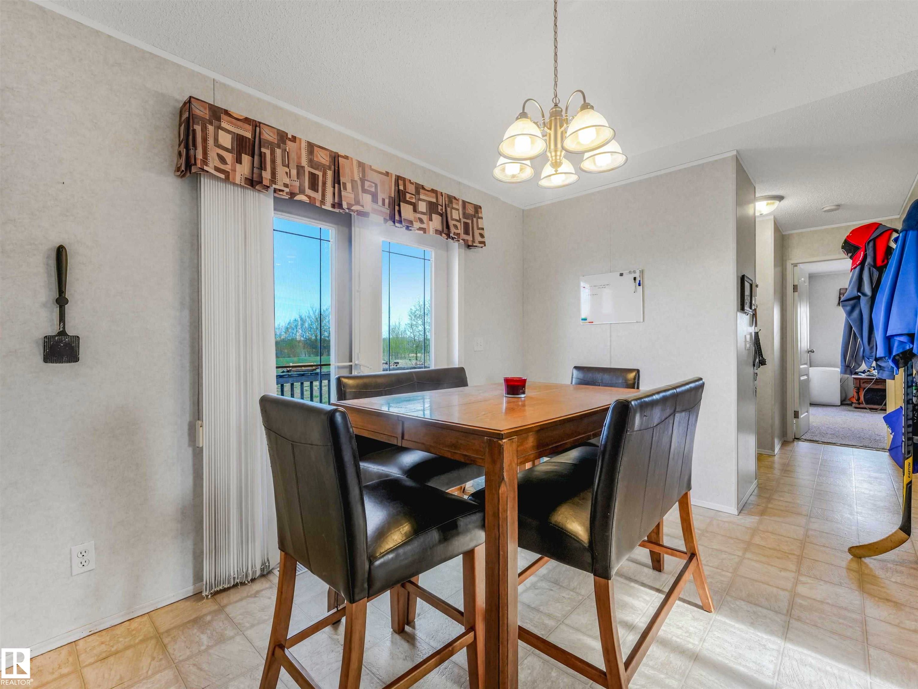 Dining area featuring light tile flooring and a patio door with full-length vertical blinds - 57016 Range Road 13, Rural Barrhead County, AB - Indoor Photo Showing Dining Room