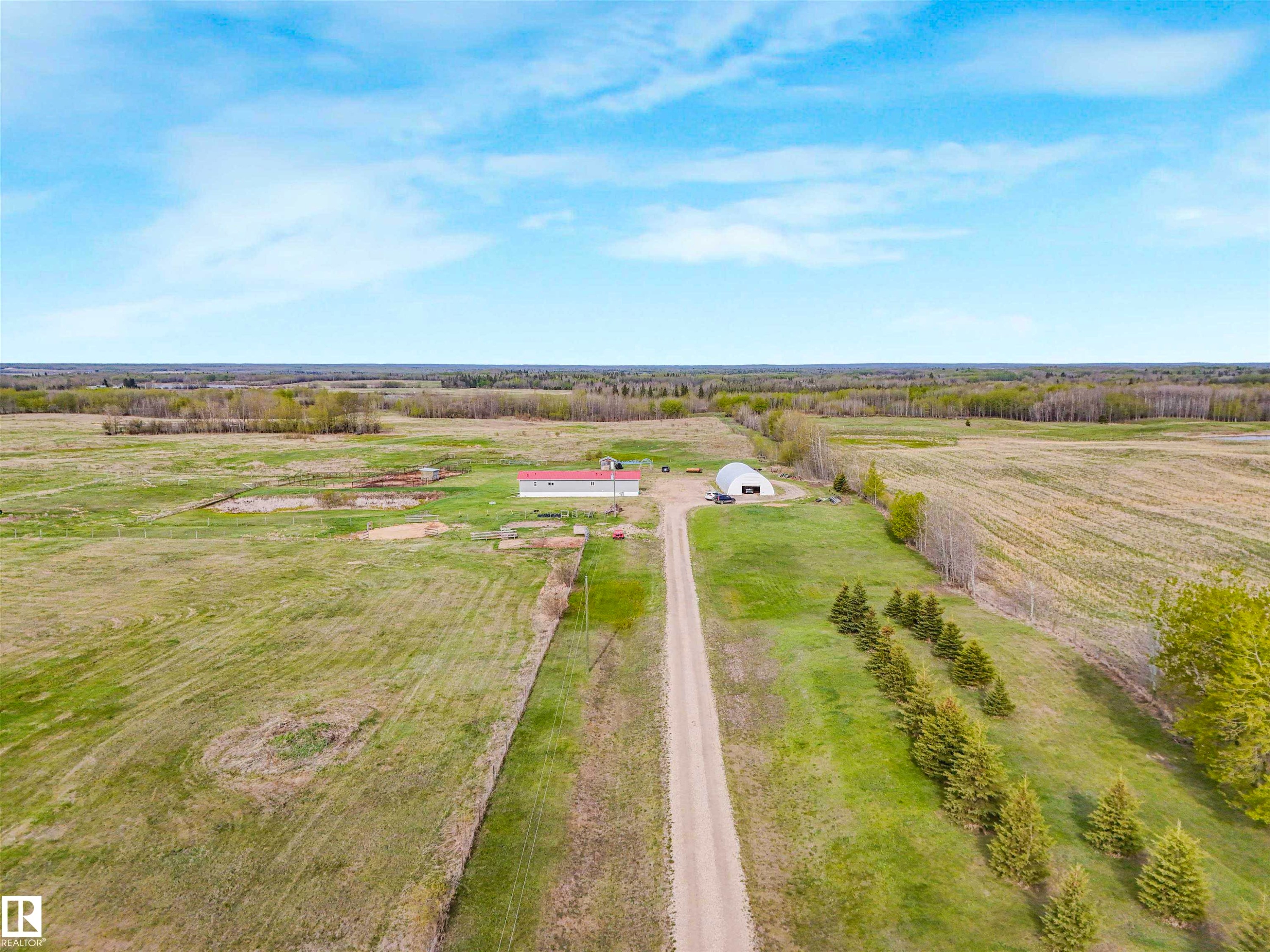 Expansive rural property featuring a long gravel driveway, a large red-roofed building, and an additional Quonset-style structure - 57016 Range Road 13, Rural Barrhead County, AB - Outdoor With View