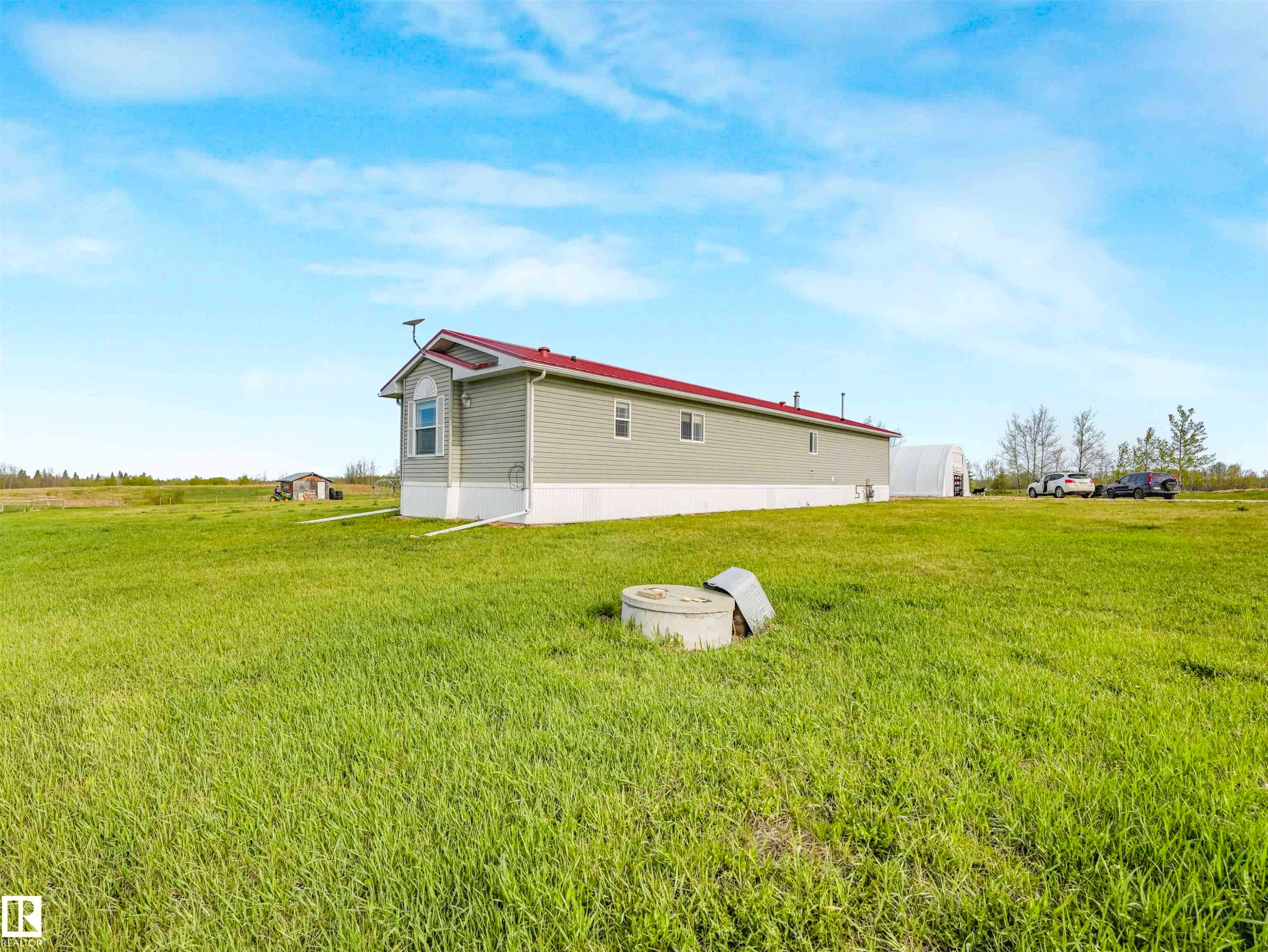 Expansive green space featuring a long-form residence with light green siding and a red roof - 57016 Range Road 13, Rural Barrhead County, AB - Outdoor
