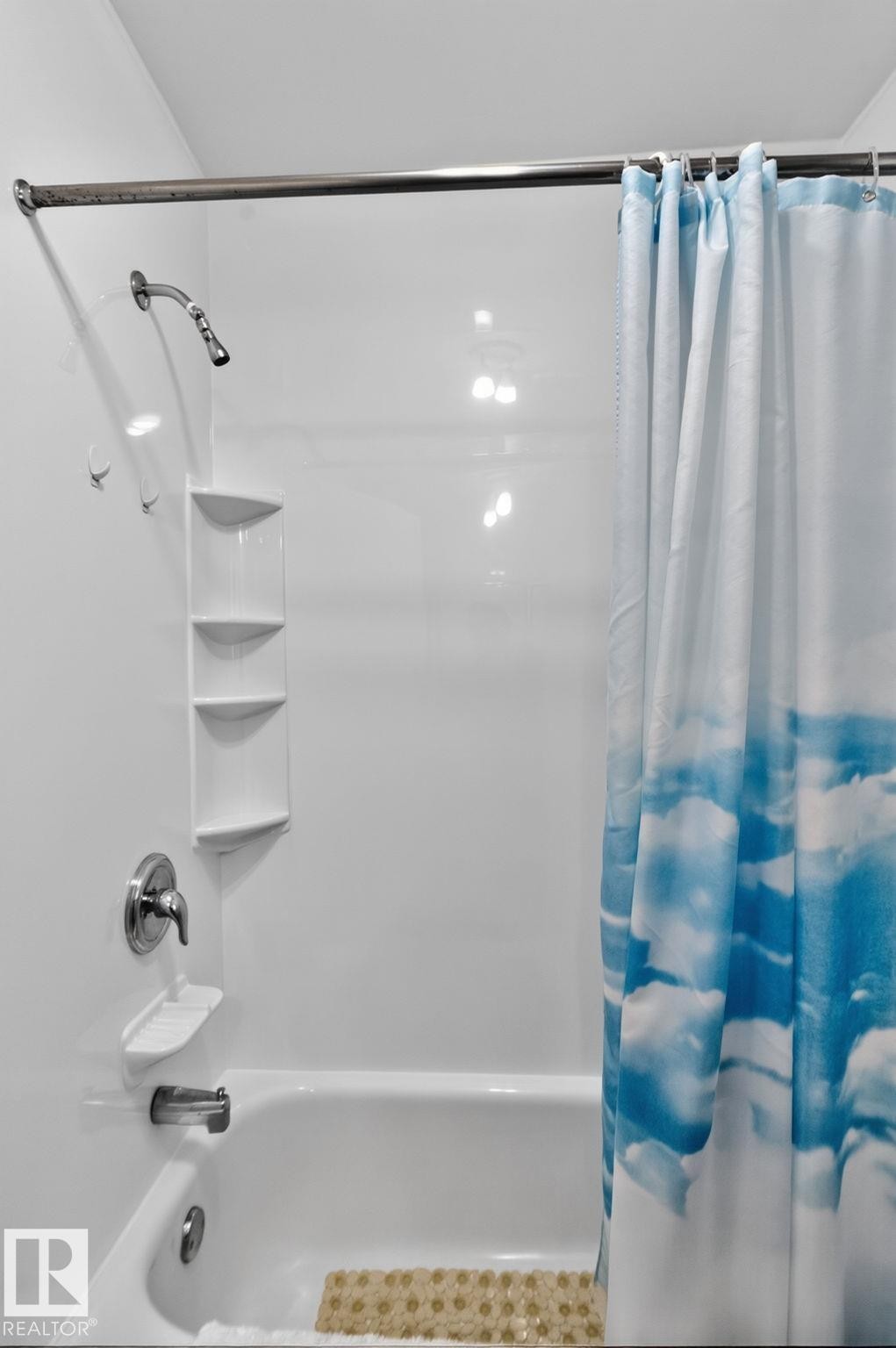 Bathtub shower combination featuring white surround, chrome fixtures, and integrated shelving - 12703 122 Street Nw, Edmonton, AB