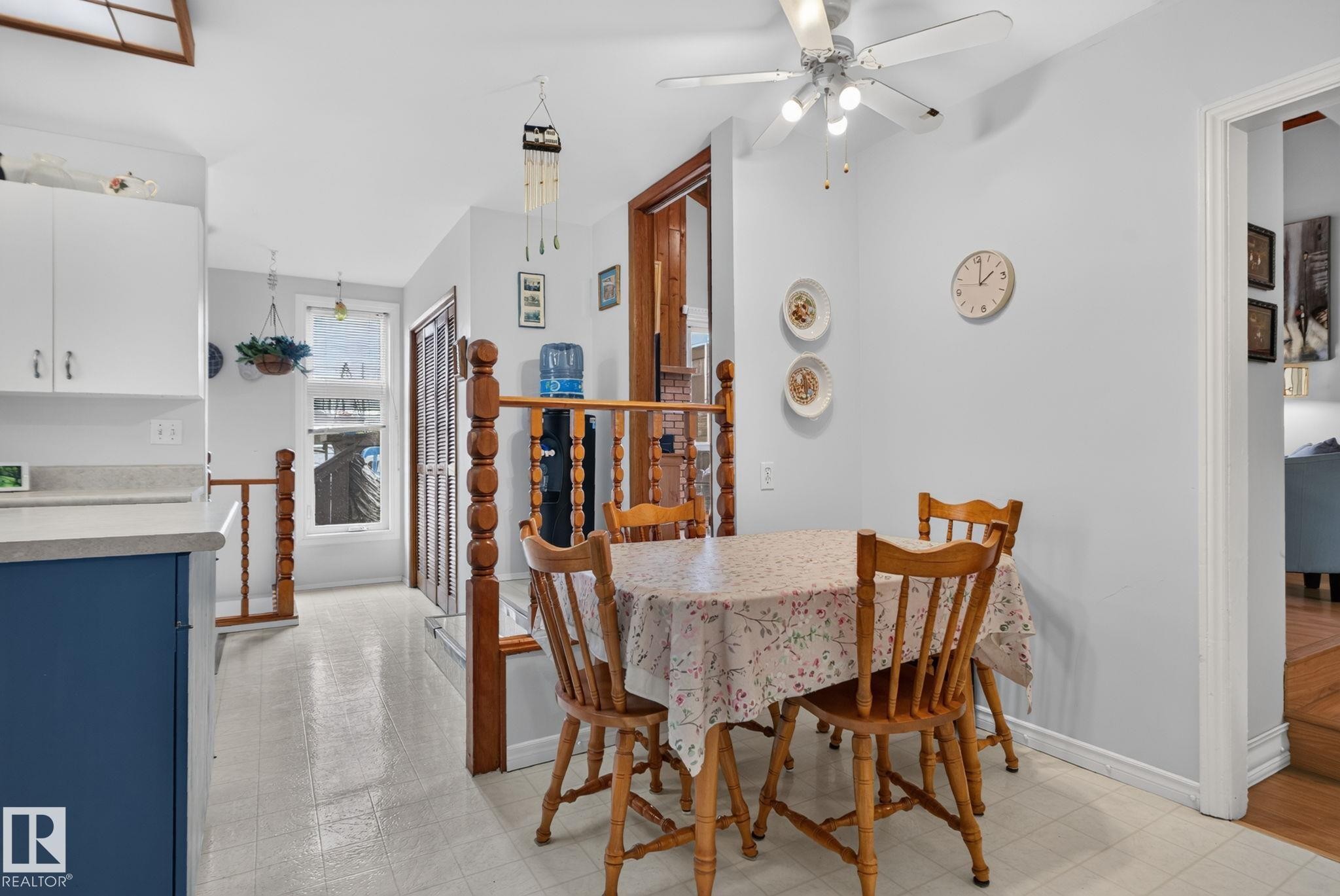 Dining area featuring a ceiling fan with integrated lighting, a half-wall with wooden balusters, and light-toned flooring - 12703 122 Street Nw, Edmonton, AB