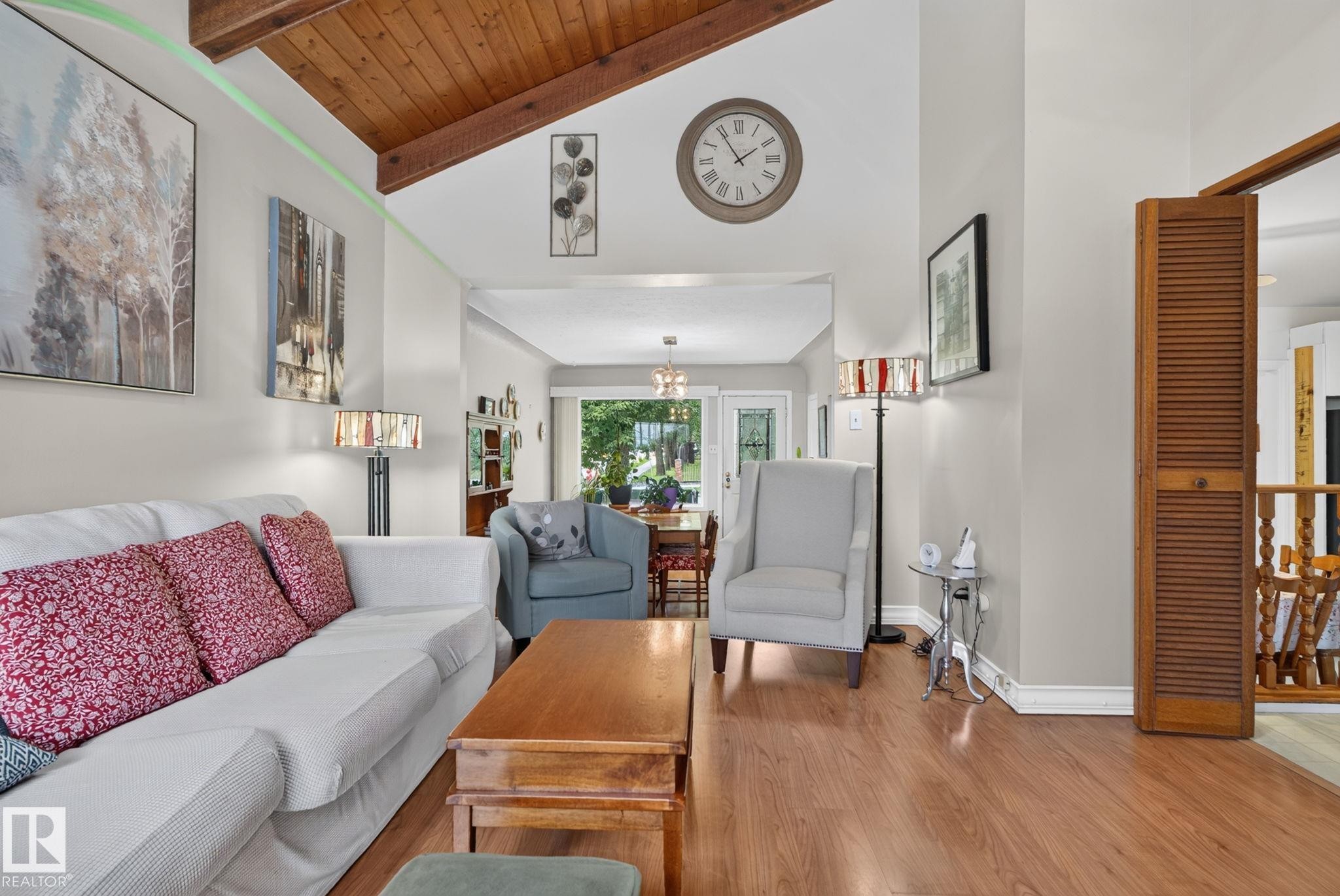 Living area with vaulted wood-beamed ceiling, wood-finish flooring, and a louvered bi-fold door - 12703 122 Street Nw, Edmonton, AB