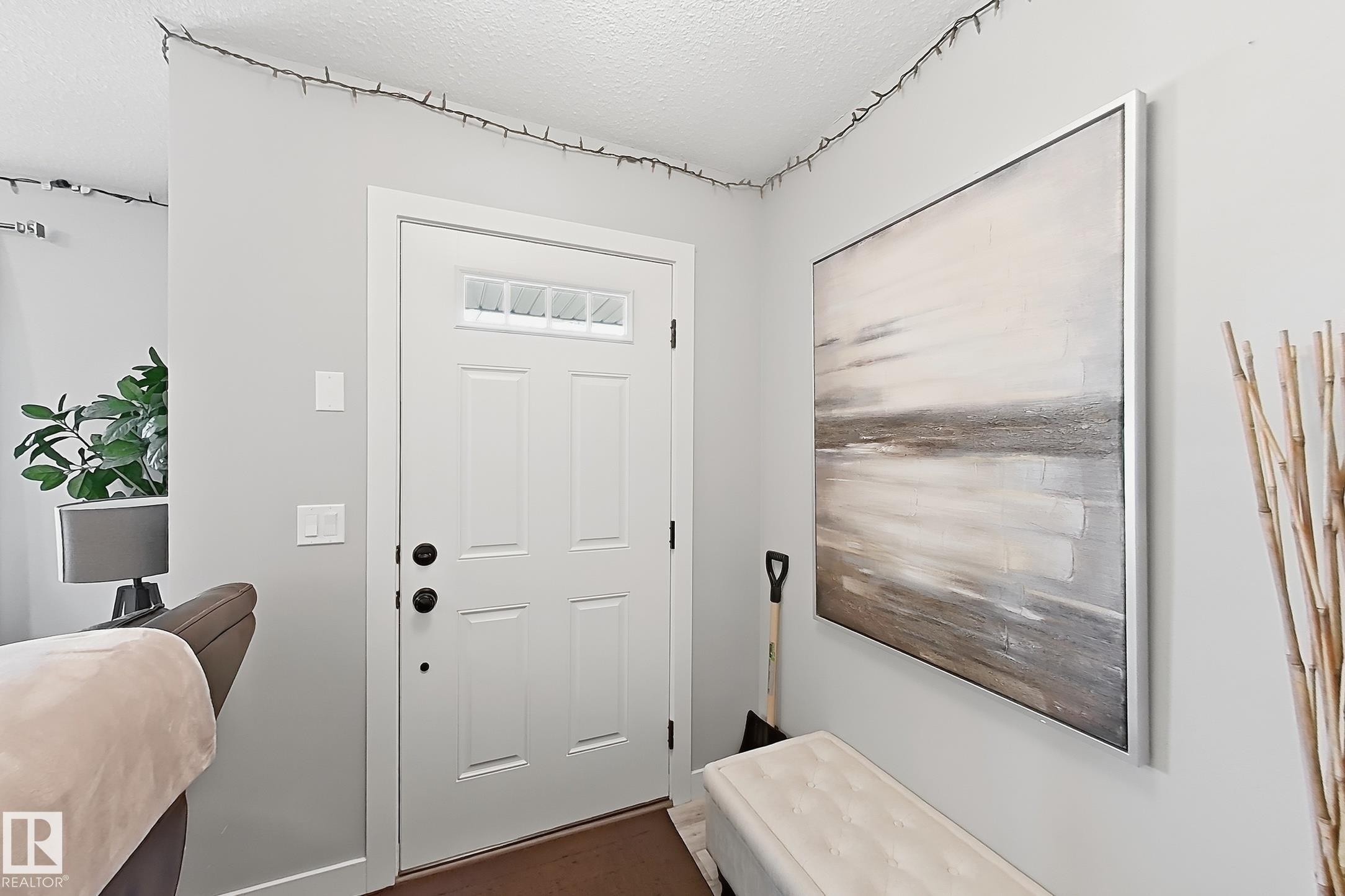Entryway featuring a white paneled door with windowed transom, dark wood-finish flooring, and light gray walls - 187 Radcliffe Wynd, Fort Saskatchewan, AB - Indoor Photo Showing Other Room