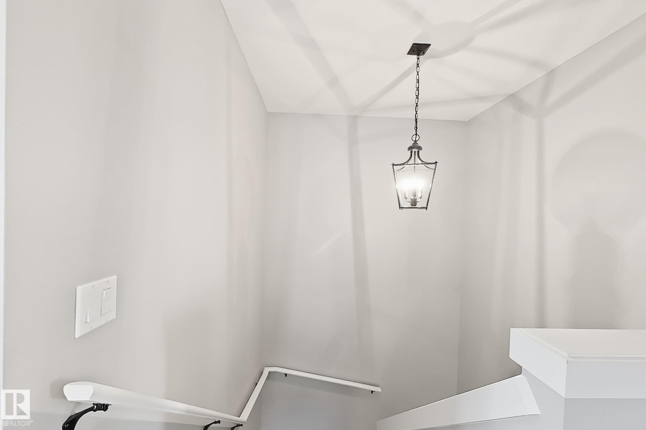 Stairwell featuring a traditional lantern-style pendant light fixture, gray painted walls, and white handrails - 187 Radcliffe Wynd, Fort Saskatchewan, AB - Indoor