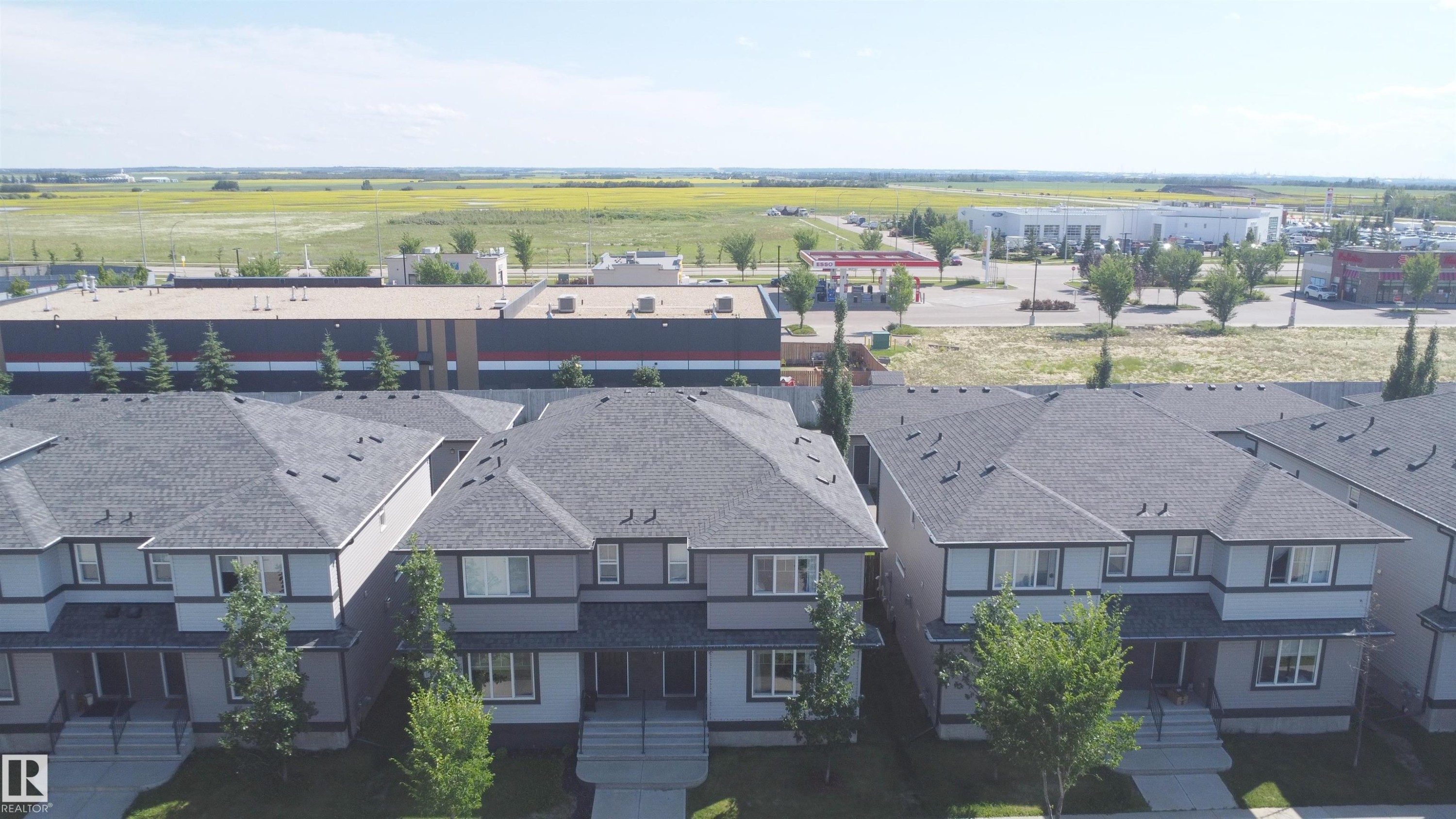Row of two-story residences featuring light gray siding and dark gray shingle roofing - 187 Radcliffe Wynd, Fort Saskatchewan, AB - Outdoor