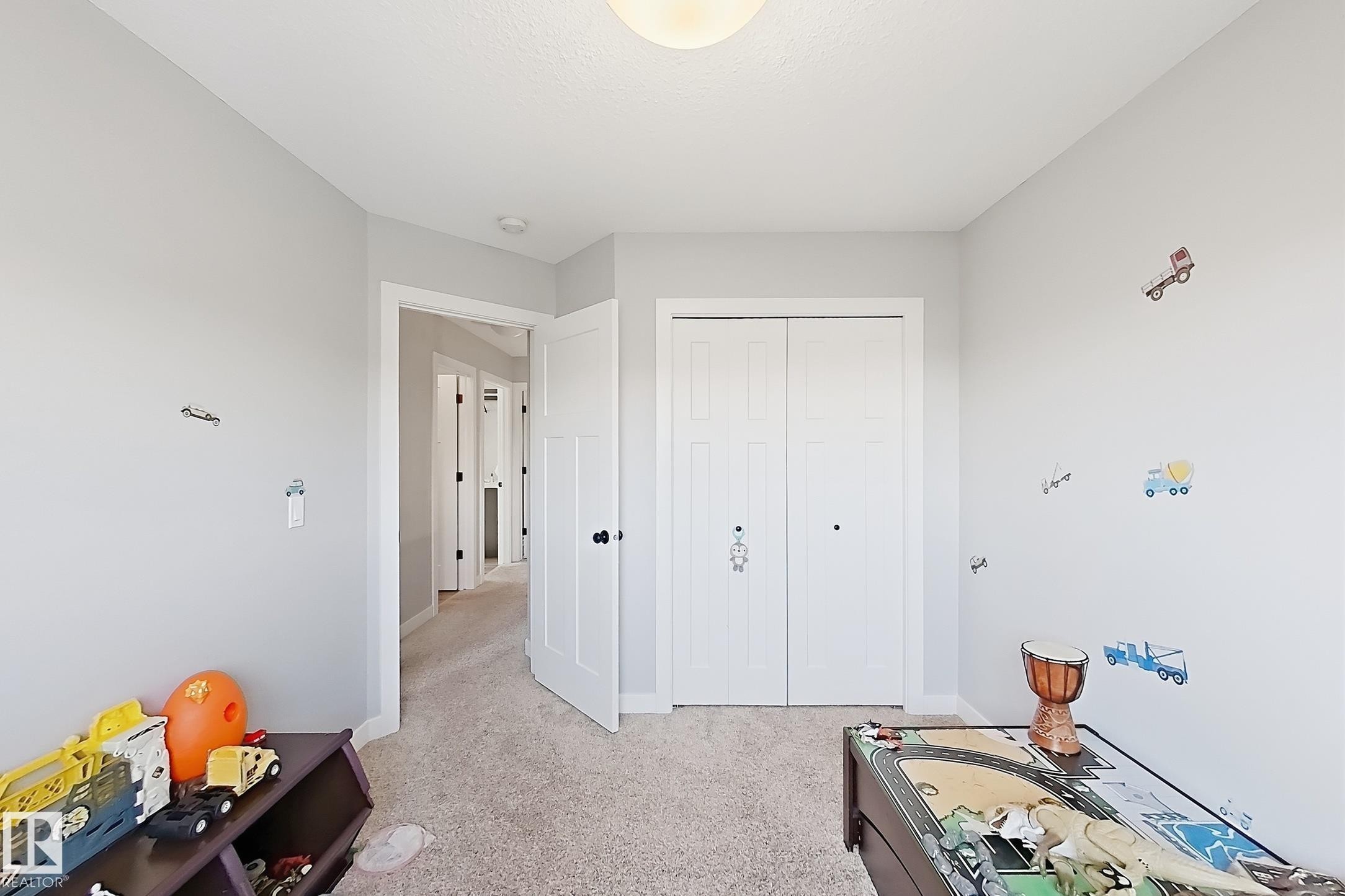 Light gray wall paint, textured ceiling, light-colored carpet, white trim, and white bi-fold closet doors - 187 Radcliffe Wynd, Fort Saskatchewan, AB - Indoor
