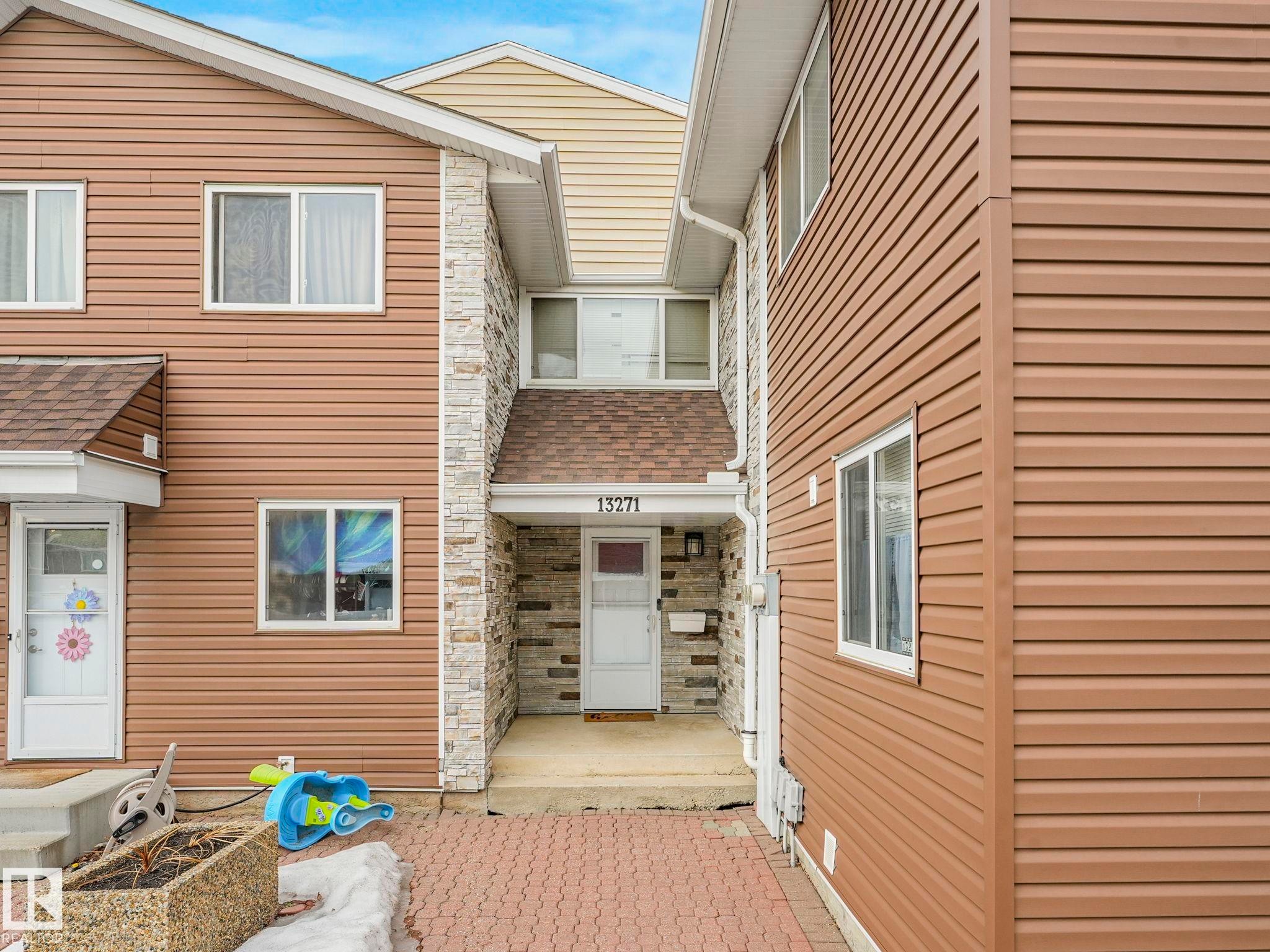 Entrance to property featuring stone siding and a shingled roof - 13271 47 Street Nw, Edmonton, AB