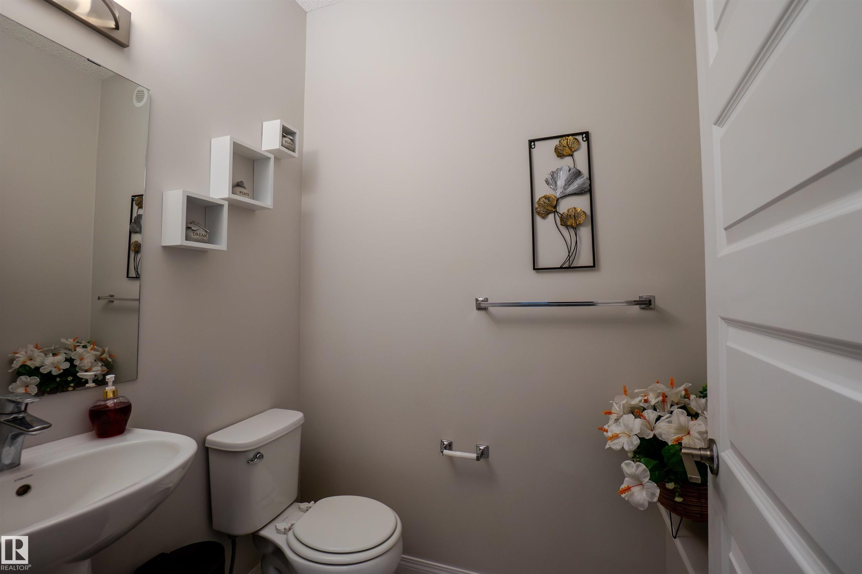 Bathroom featuring a pedestal sink, wall-mounted mirror, and a white toilet - 1766 Dumont Crescent Sw, Edmonton, AB - Indoor Photo Showing Bathroom