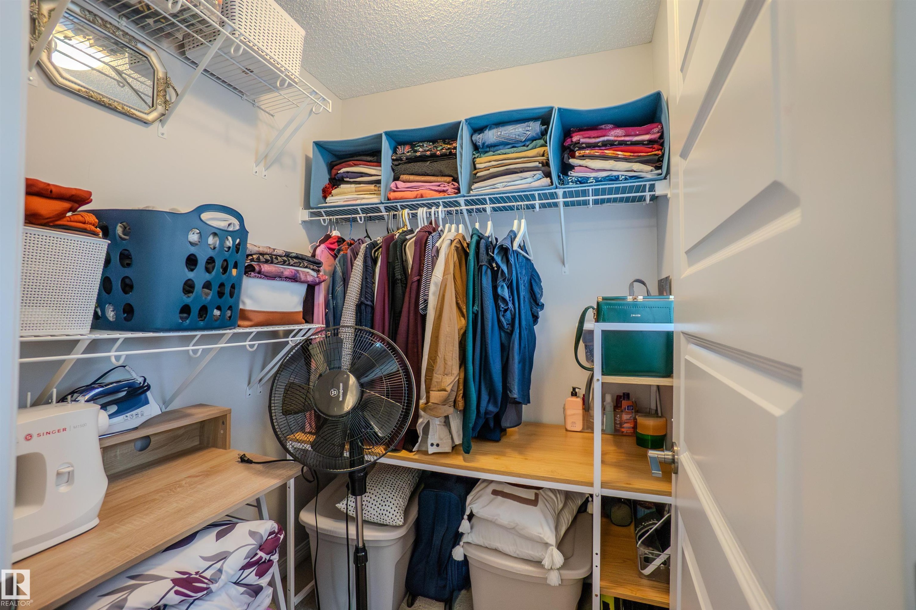 Custom closet system featuring multiple wire shelves, hanging rods, and a built-in wood-finish countertop - 1766 Dumont Crescent Sw, Edmonton, AB - Indoor With Storage