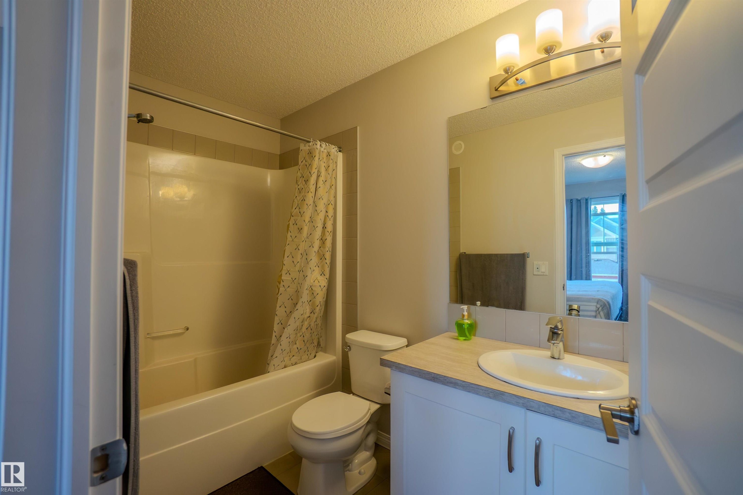 Full bathroom featuring a single vanity with under-sink cabinetry, a full bathtub with shower, and a built-in toilet - 1766 Dumont Crescent Sw, Edmonton, AB - Indoor Photo Showing Bathroom