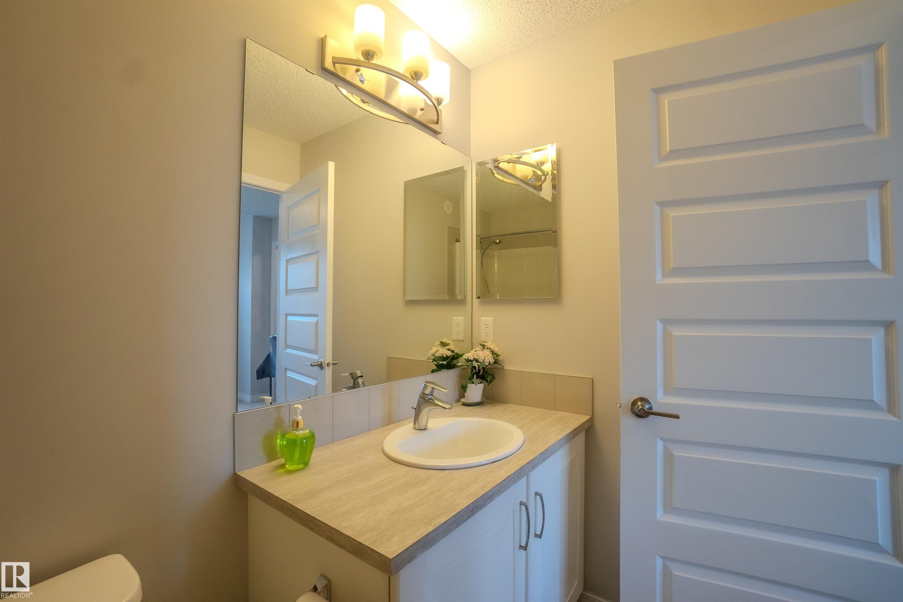 Bathroom vanity featuring a white ceramic sink, chrome faucet, and integrated cabinetry - 1766 Dumont Crescent Sw, Edmonton, AB - Indoor Photo Showing Bathroom