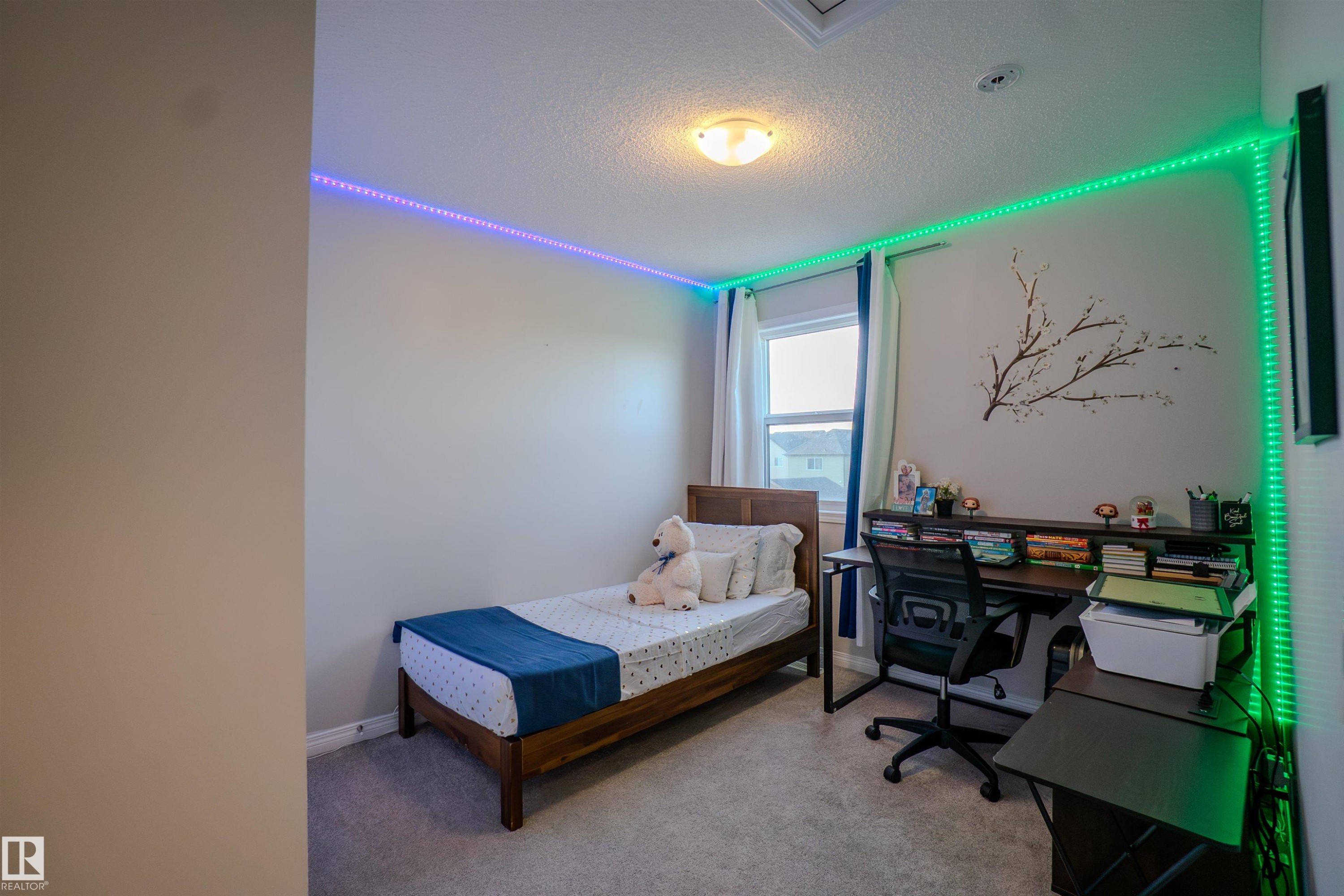 Carpeted room featuring a single window with curtain rods and drapes, a flush-mount ceiling light fixture, and perimeter wall-mounted lighting strips - 1766 Dumont Crescent Sw, Edmonton, AB - Indoor Photo Showing Bedroom