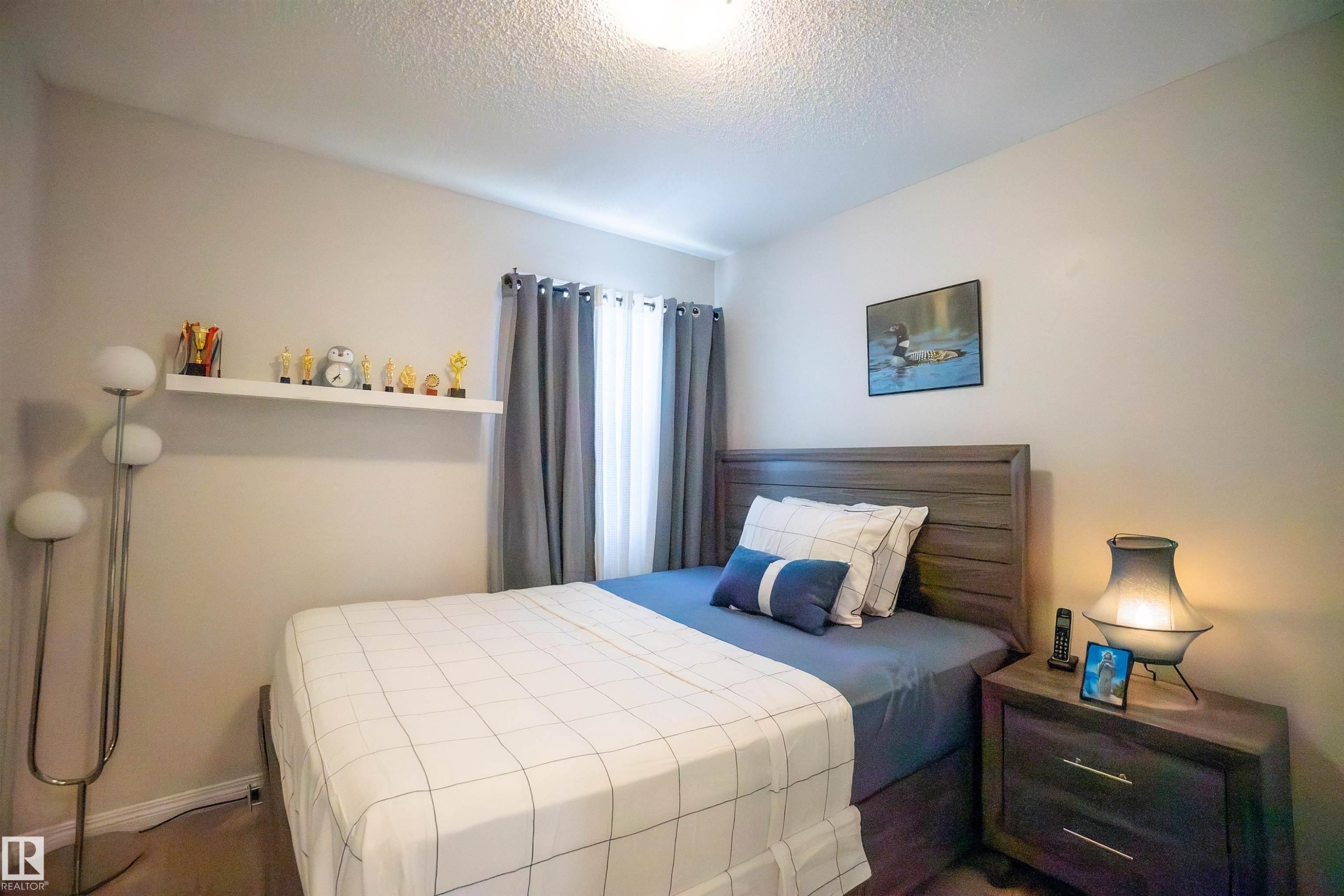 Bedroom with wood-finish flooring, a window with drapery, a built-in wall shelf, and a ceiling-mounted light fixture - 1766 Dumont Crescent Sw, Edmonton, AB - Indoor Photo Showing Bedroom