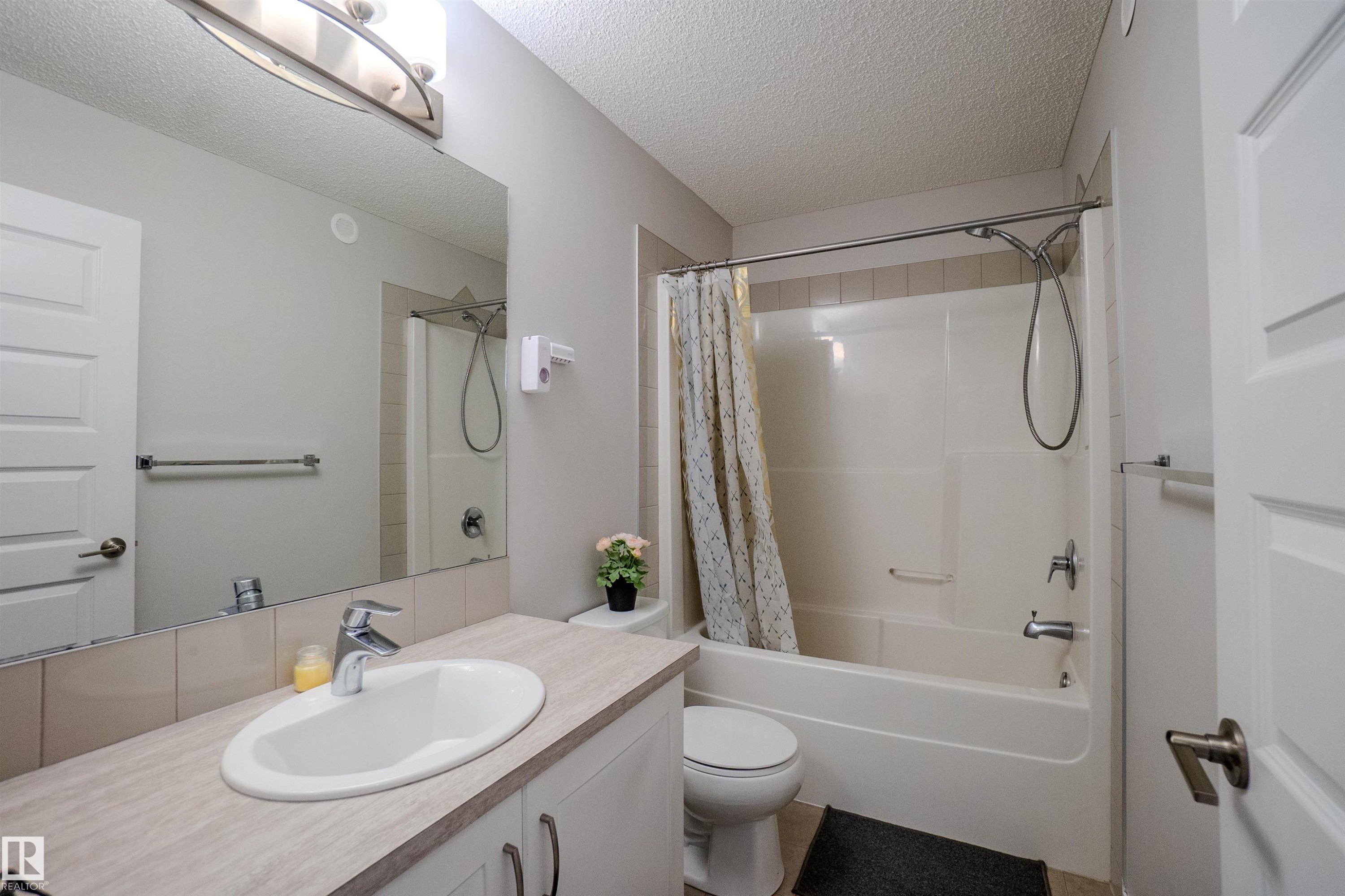 Bathroom featuring a vanity with a laminate countertop, an undermount sink, and a large wall mirror - 1766 Dumont Crescent Sw, Edmonton, AB - Indoor Photo Showing Bathroom