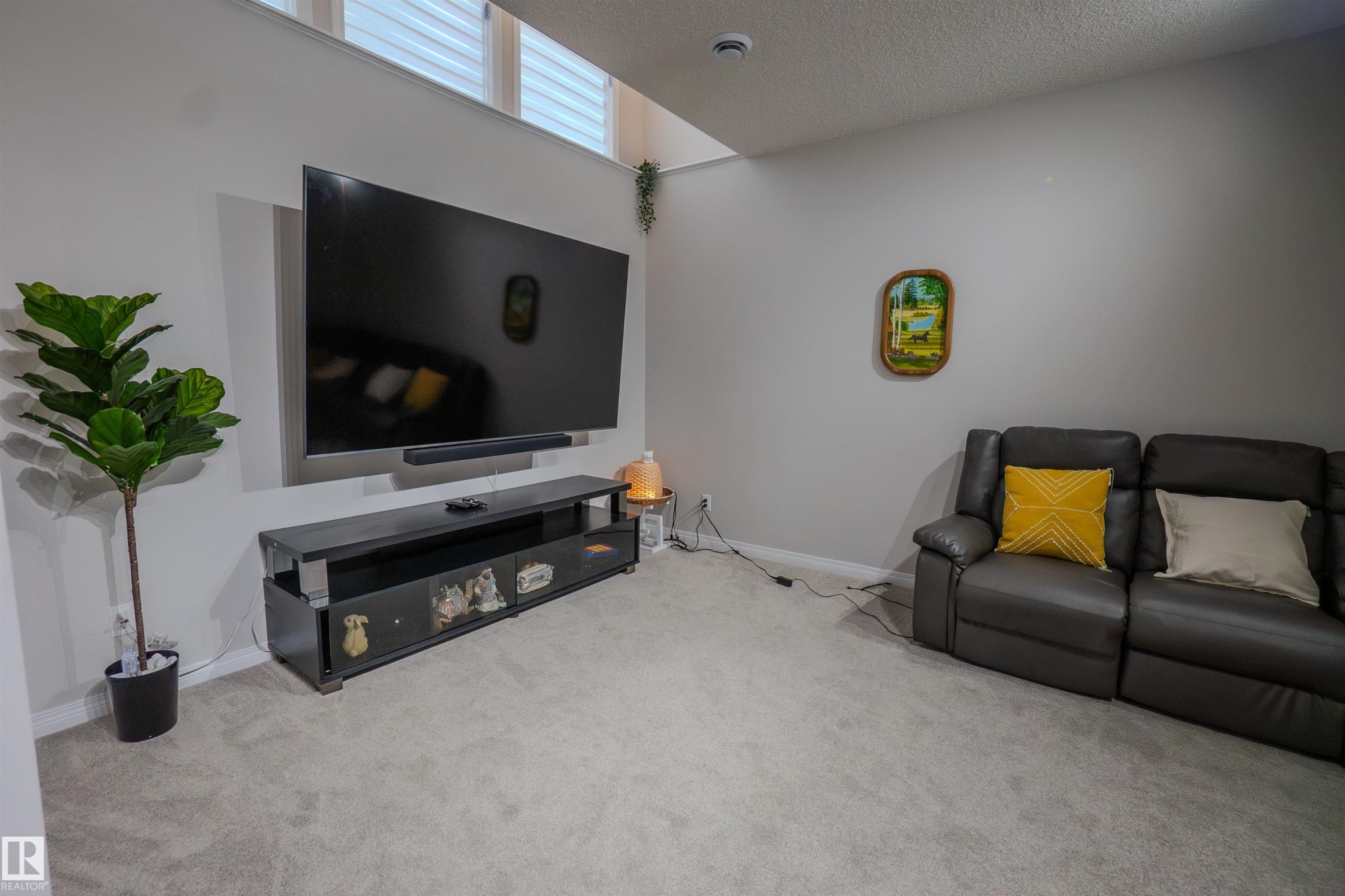 Wall-mounted television with soundbar positioned above a dark media console - 1766 Dumont Crescent Sw, Edmonton, AB - Indoor