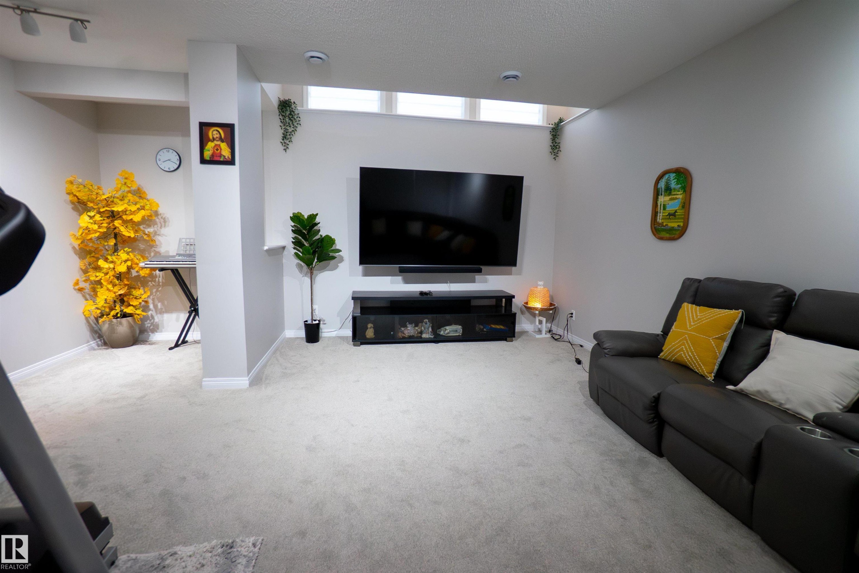 Spacious recreation room featuring light gray carpeting and white baseboards - 1766 Dumont Crescent Sw, Edmonton, AB - Indoor