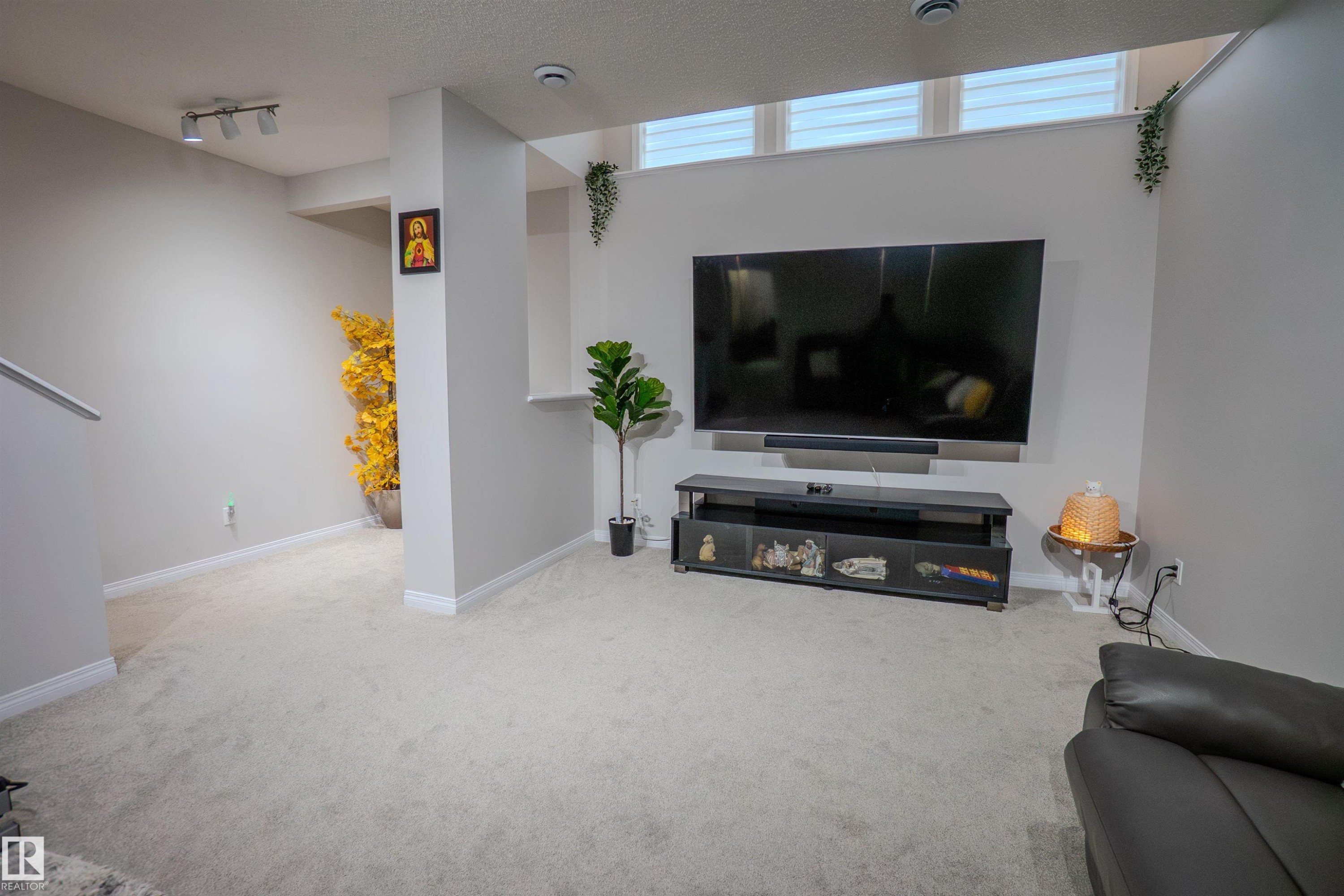 Carpeted recreation area with light gray walls, white trim, track lighting, and a transom window band - 1766 Dumont Crescent Sw, Edmonton, AB - Indoor Photo Showing Other Room