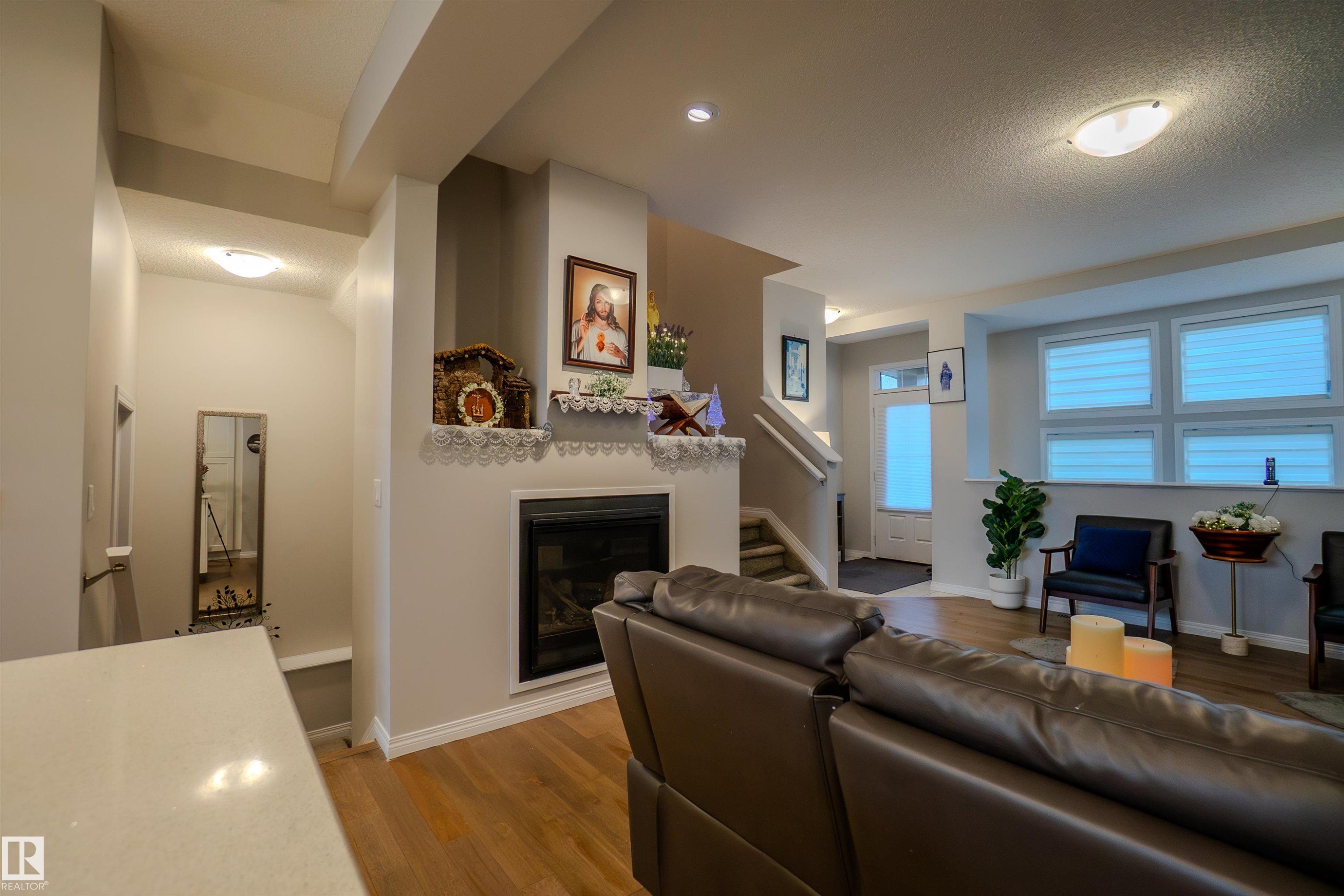 Living area featuring wood-finish flooring and a contemporary fireplace with a decorative mantel - 1766 Dumont Crescent Sw, Edmonton, AB - Indoor Photo Showing Living Room With Fireplace
