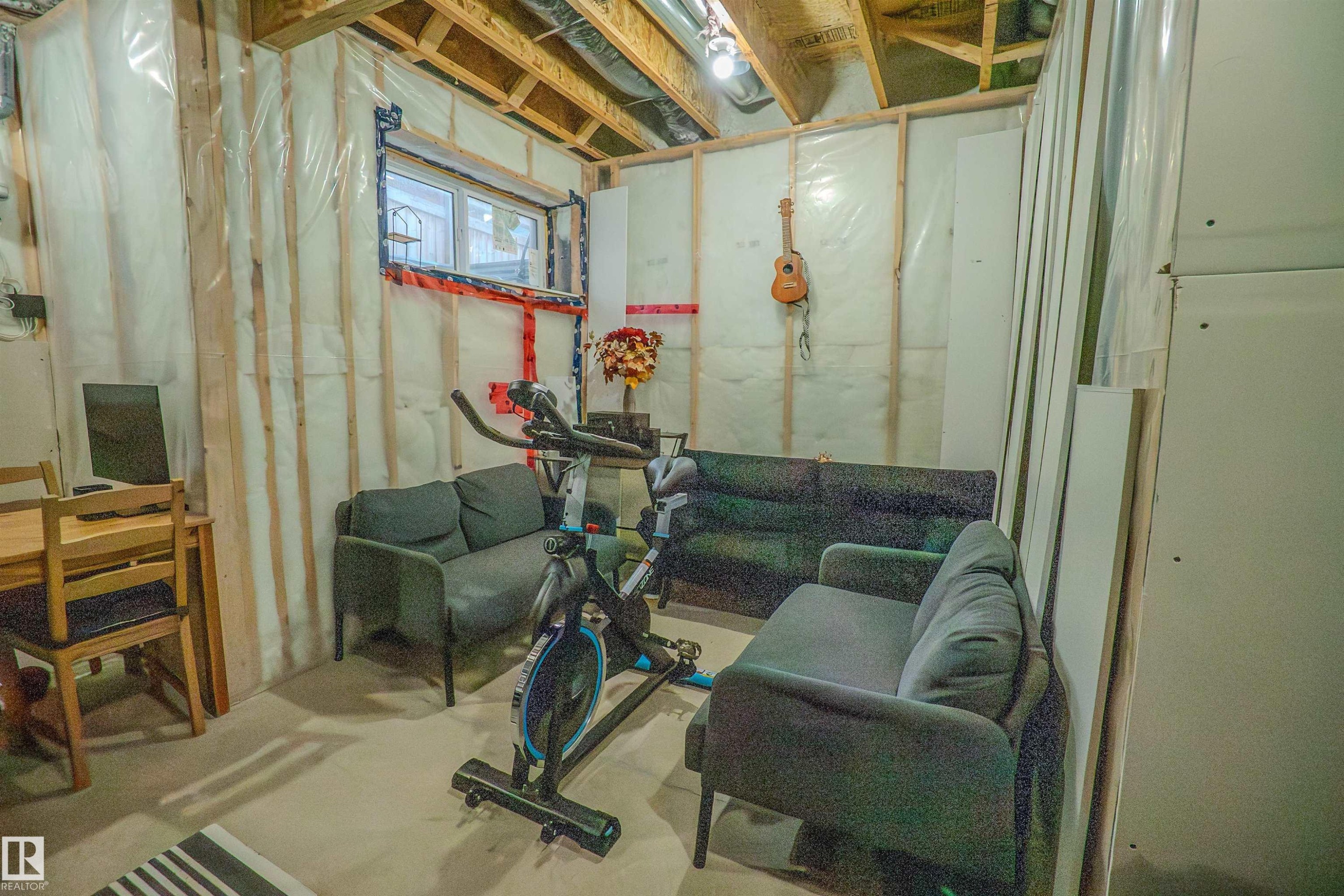 Unfinished basement space featuring exposed wooden ceiling joists, insulated walls with vapor barrier, and a small egress window - 1766 Dumont Crescent Sw, Edmonton, AB - Indoor Photo Showing Basement