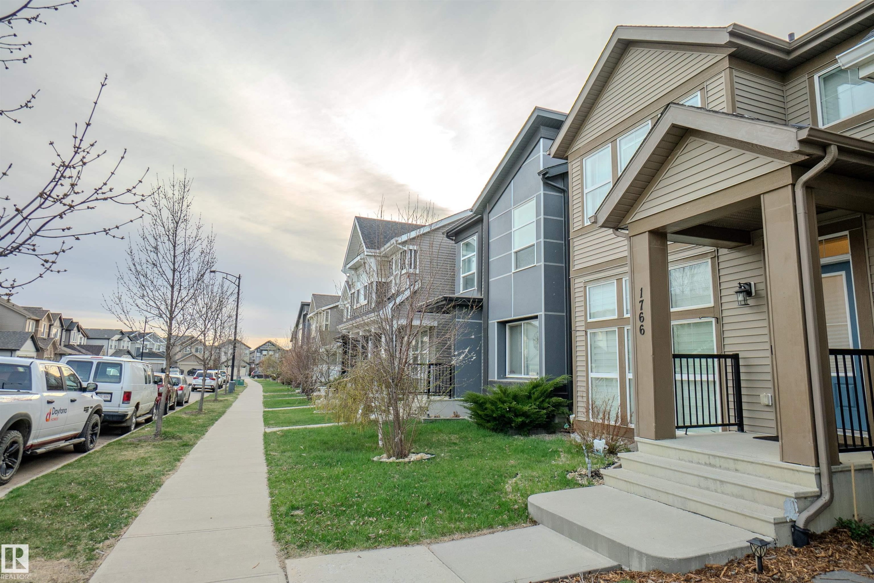 Two-story property featuring light brown horizontal siding, a covered entry porch with black metal railings, and concrete front steps - 1766 Dumont Crescent Sw, Edmonton, AB - Outdoor With Facade