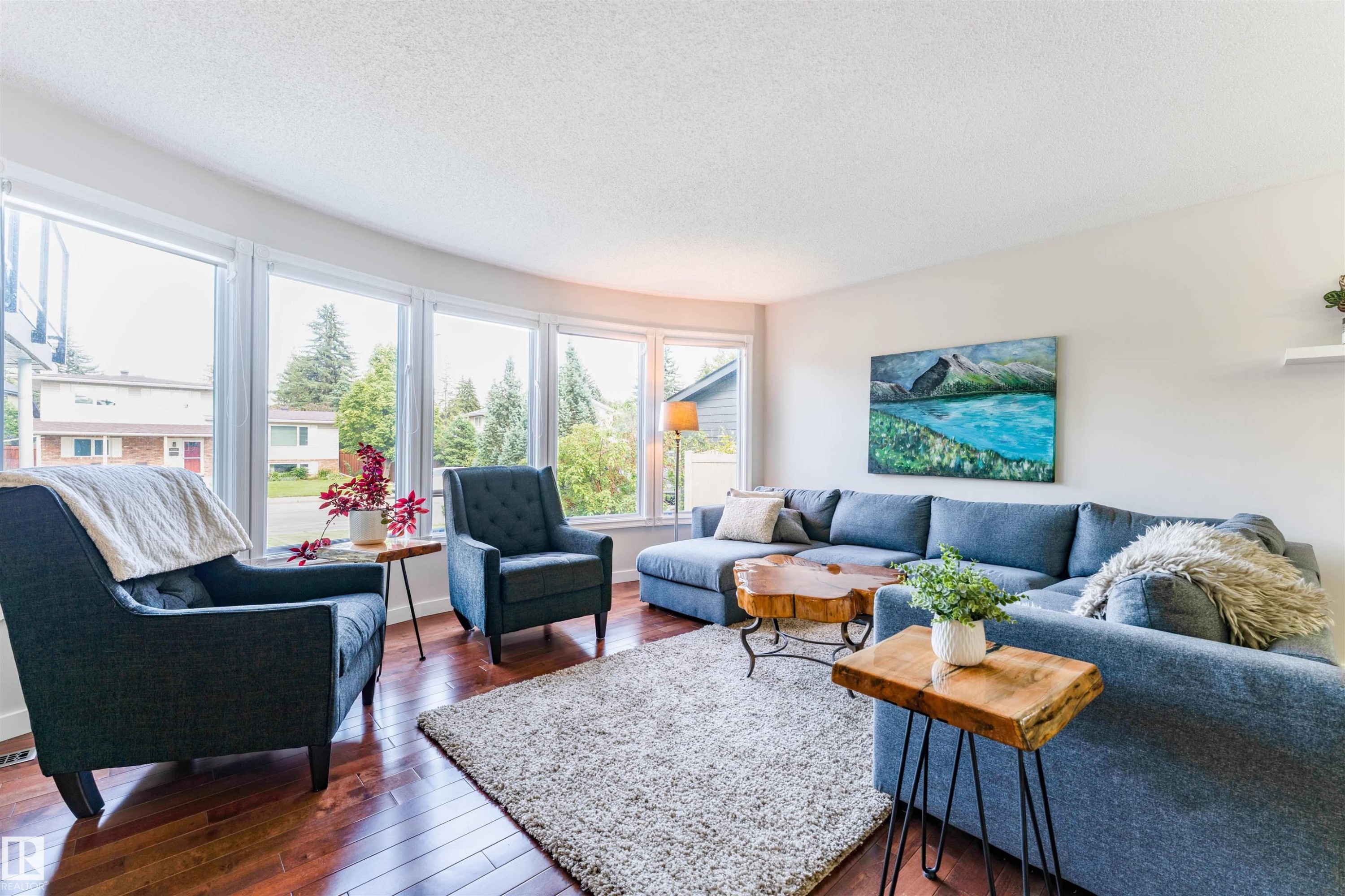Living area featuring a curved wall of large windows, wood-finish flooring, light neutral-toned walls, and a recessed ceiling - 5212 142 Street Nw, Edmonton, AB
