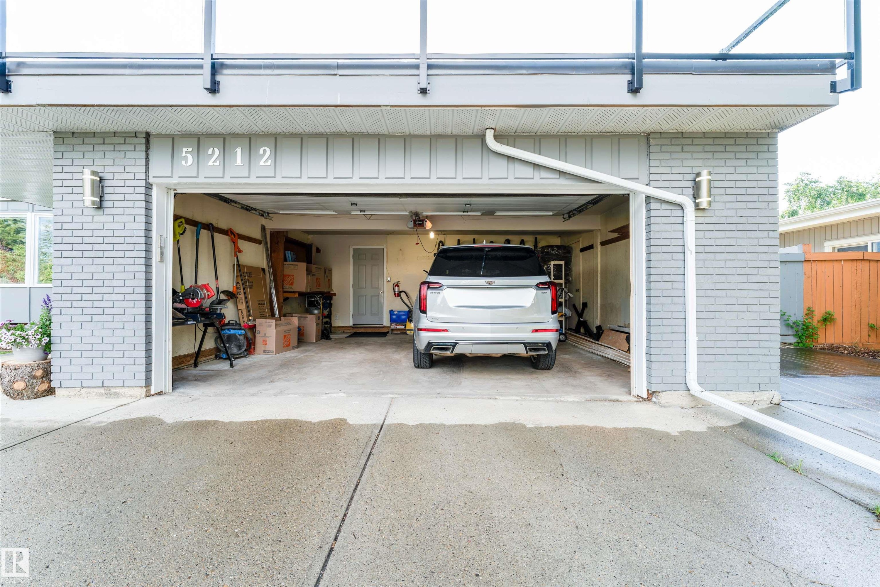 Attached two-car garage featuring a concrete driveway and light gray brick exterior - 5212 142 Street Nw, Edmonton, AB